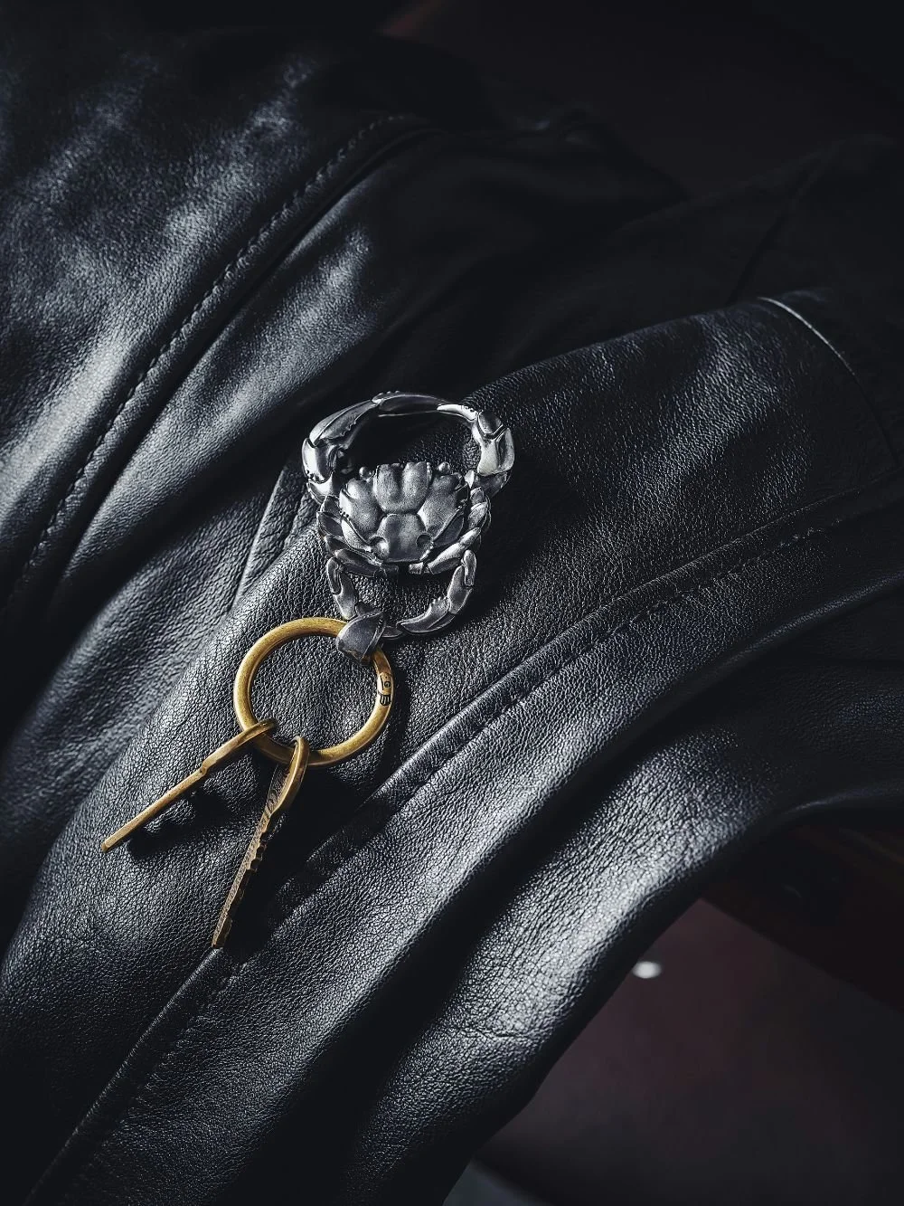 Stylish crab-shaped keychain on leather, minimal aesthetic detail shot reflecting organization and identity of a time management coach.