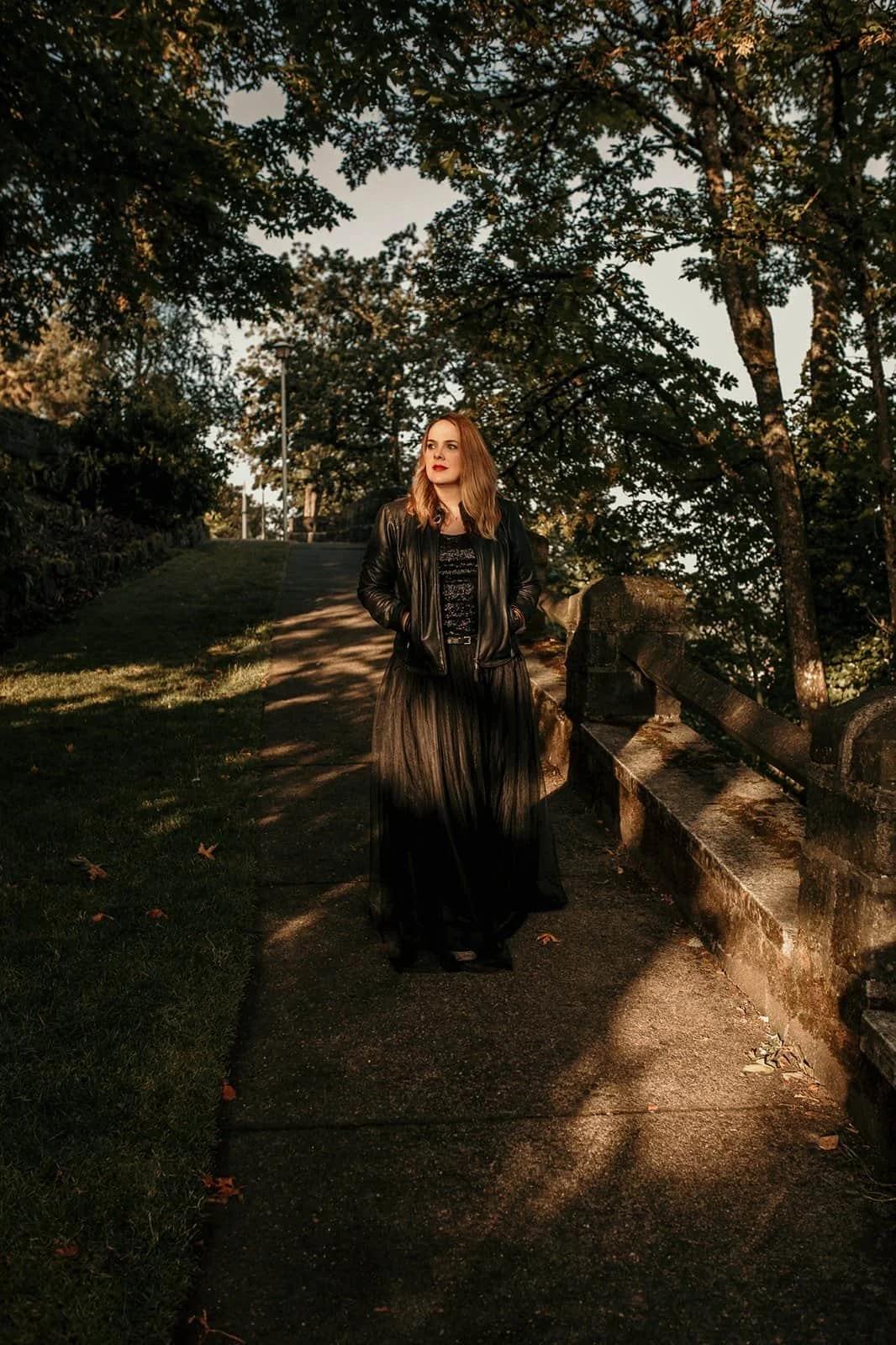 Cara Chace standing on a sun dappled path in an all black outfit showing how to manage work life balance for a woman