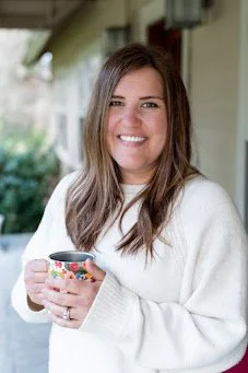 Jenny Weekes, a coaching client of Cara Chace, holding a coffee mug in a white sweater