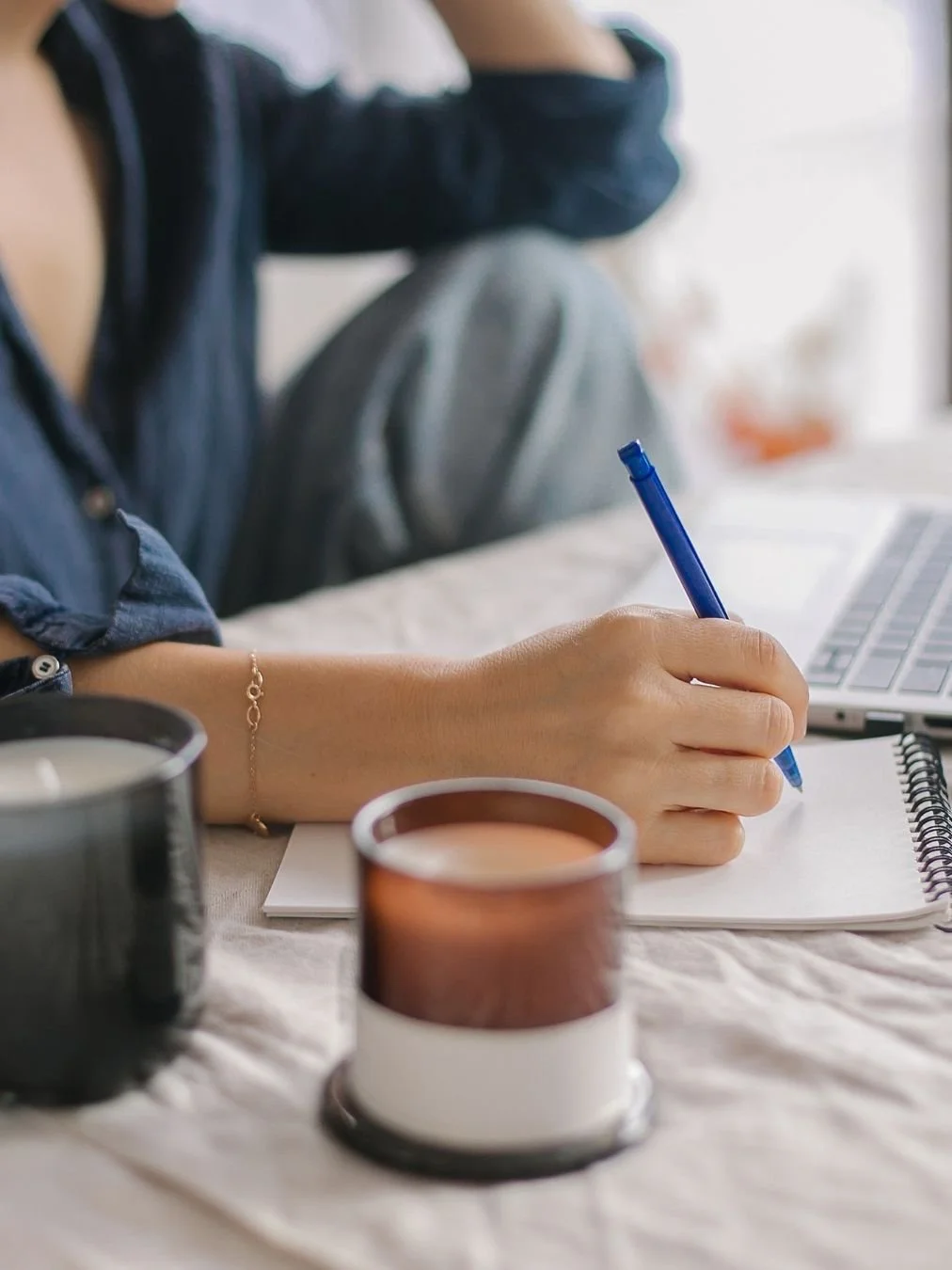 Woman entrepreneur close up of her hand writing in a notepad next to her laptop, inspired by learning work life balance self employed skills