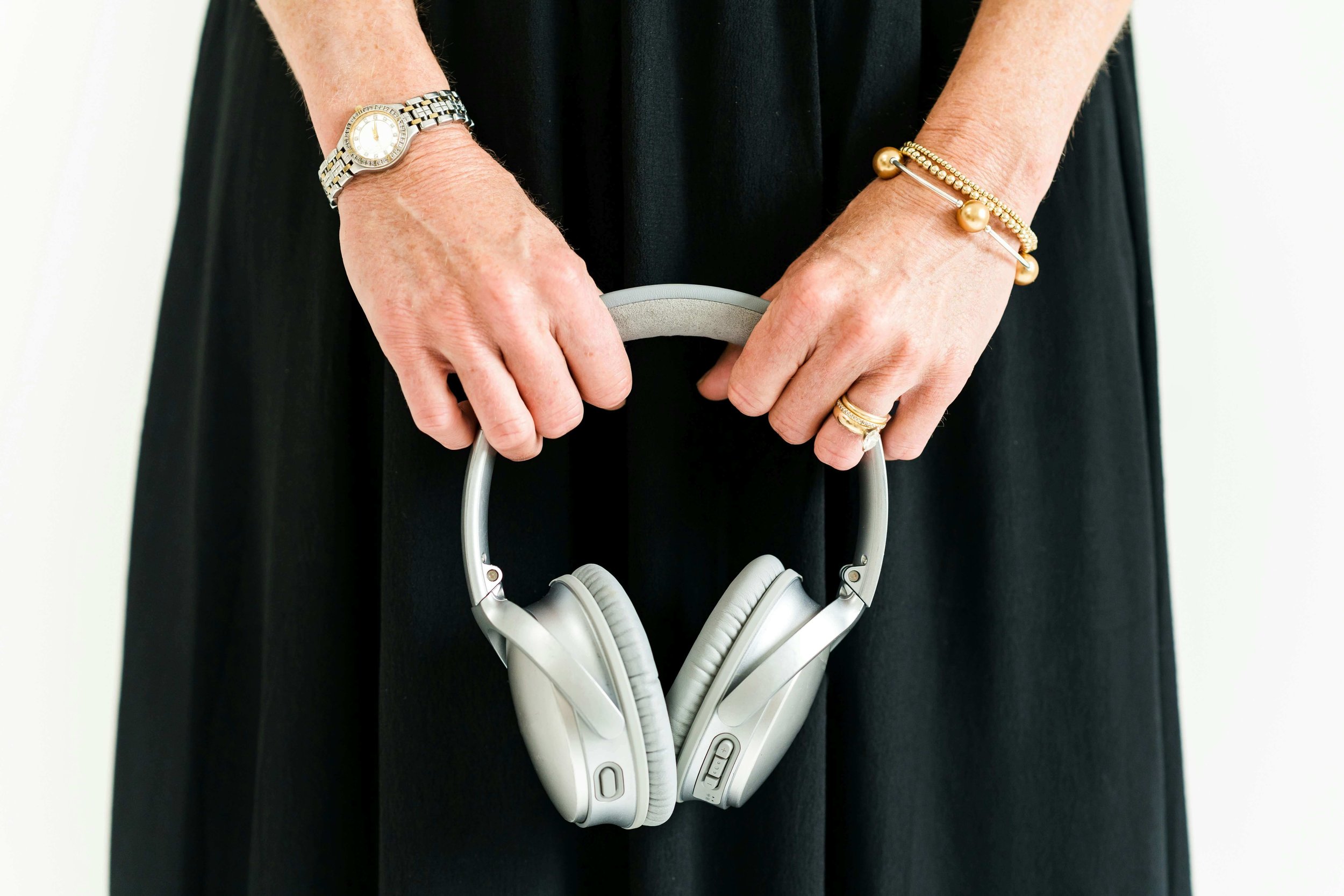 Hands holding silver headphones, for the Ditch the Chaos podcast with Cara Chace