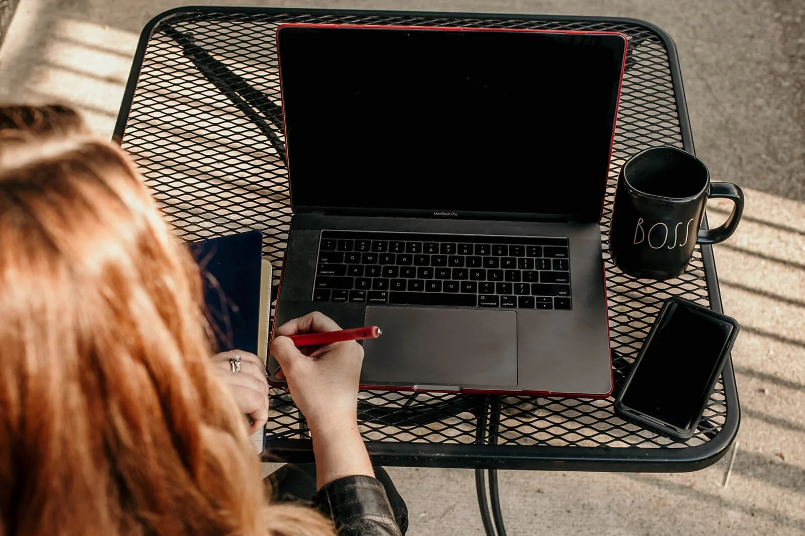Cara Chace woman entrepreneur at an outside table on a laptop with a notebook and pen symbolizing working as a time management coach