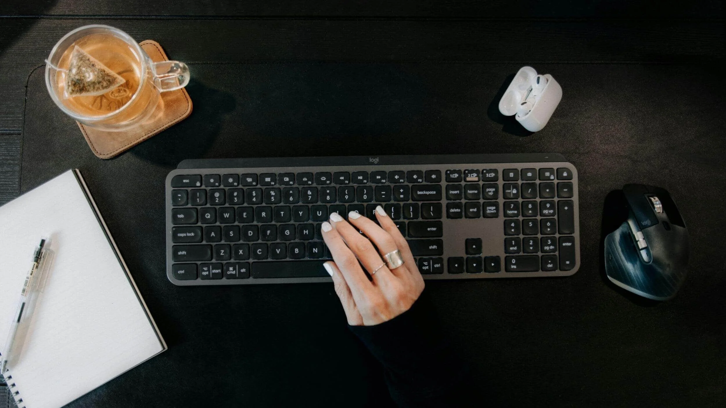 Workspace with keyboard, tea, and notebook neatly arranged, showcasing organized workflow inspired by a business coach