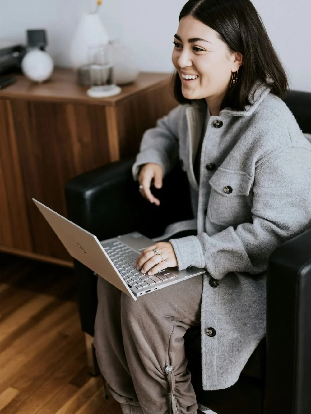 Woman business owner in a gray coat working through her marketing plan on a laptop