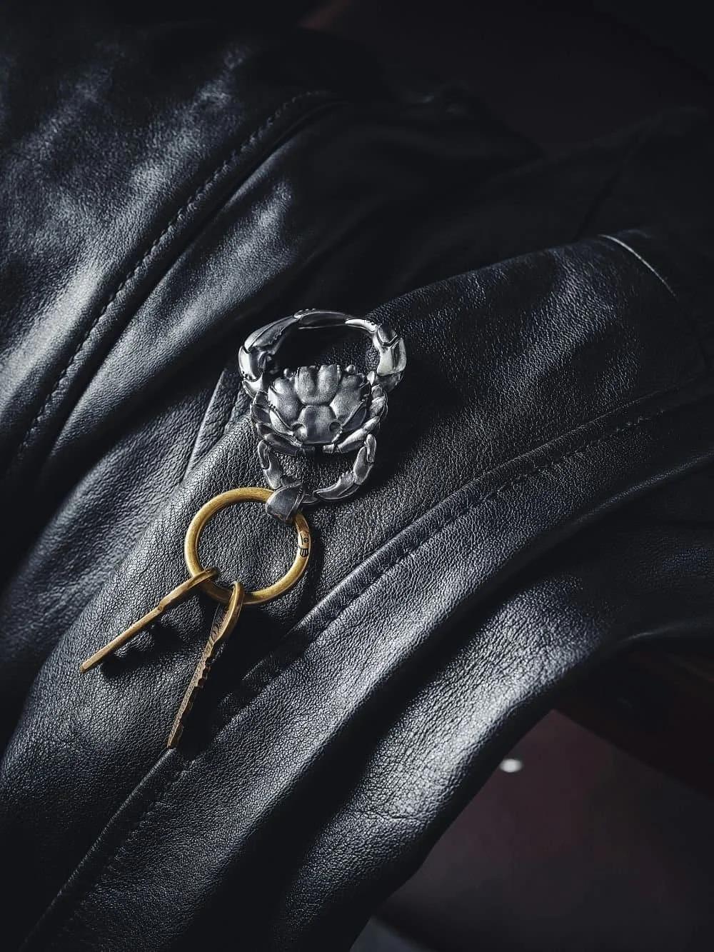 Stylish crab-shaped keychain on leather, minimal aesthetic detail shot reflecting organization and identity of a time management coach.