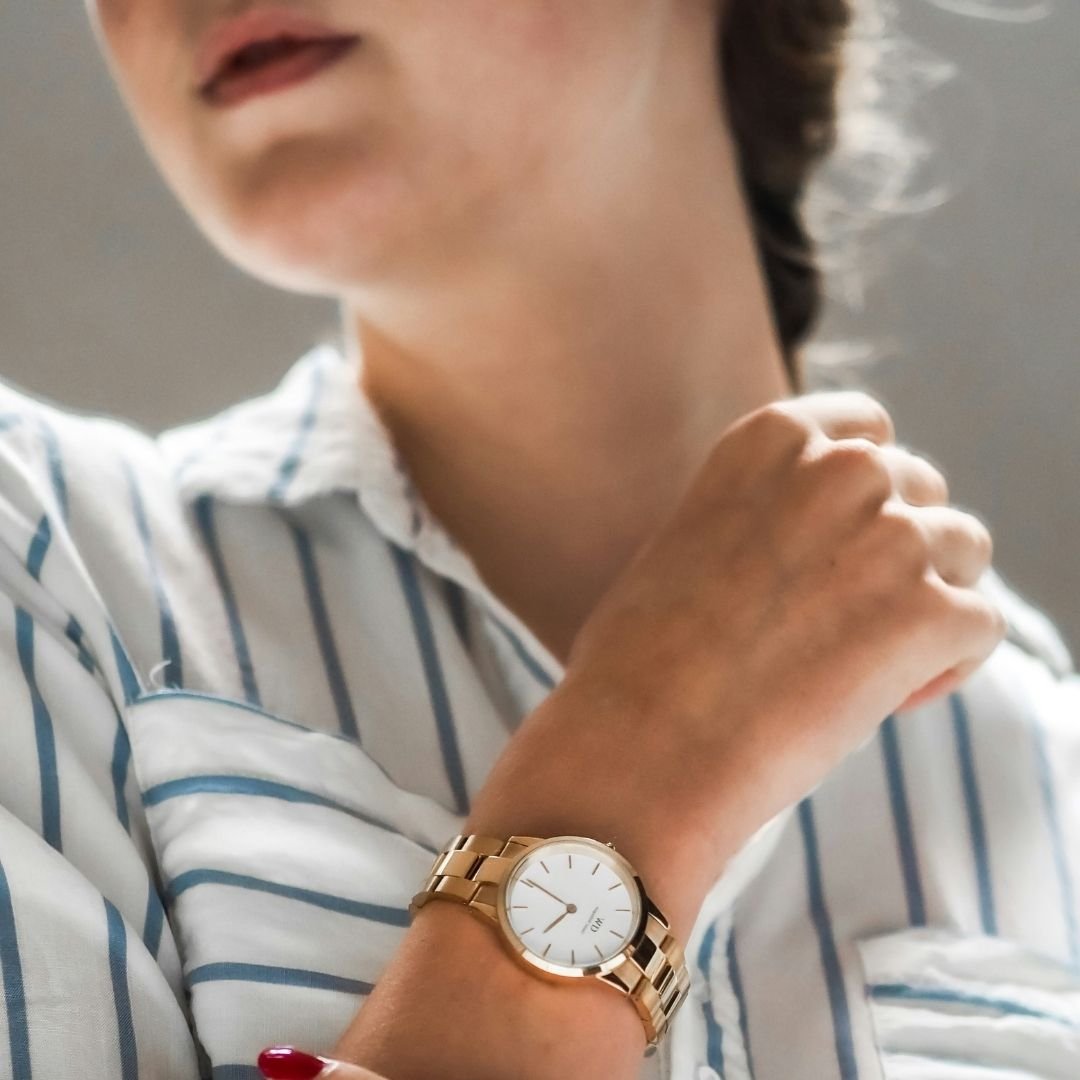 Close-up of a woman entrepreneur wearing a gold watch, striped shirt — time management coaching for women in business.