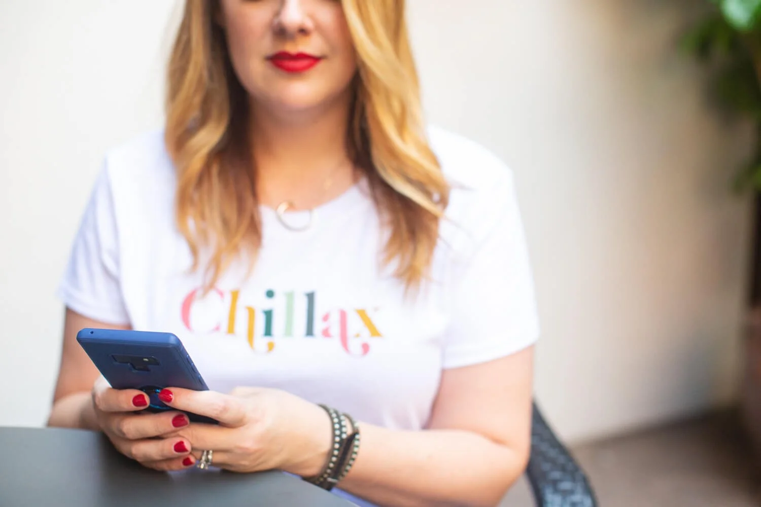 Cara Chace wearing a tshirt that says 'chillax' on her phone, representing her approach to time management coaching