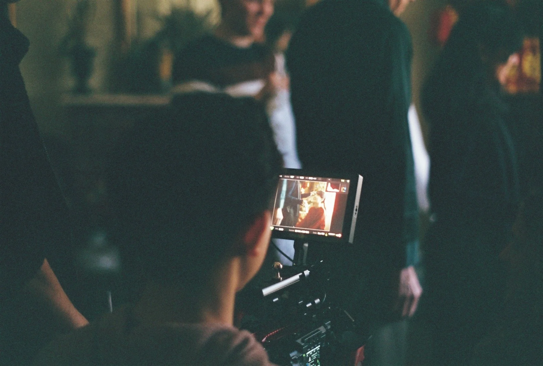 BTS of a feature film production called To Spark a Wildfire, directed by Musashi Wakaki. A film crew member operating a camera on set, capturing shots of people in a scene with blurred background.