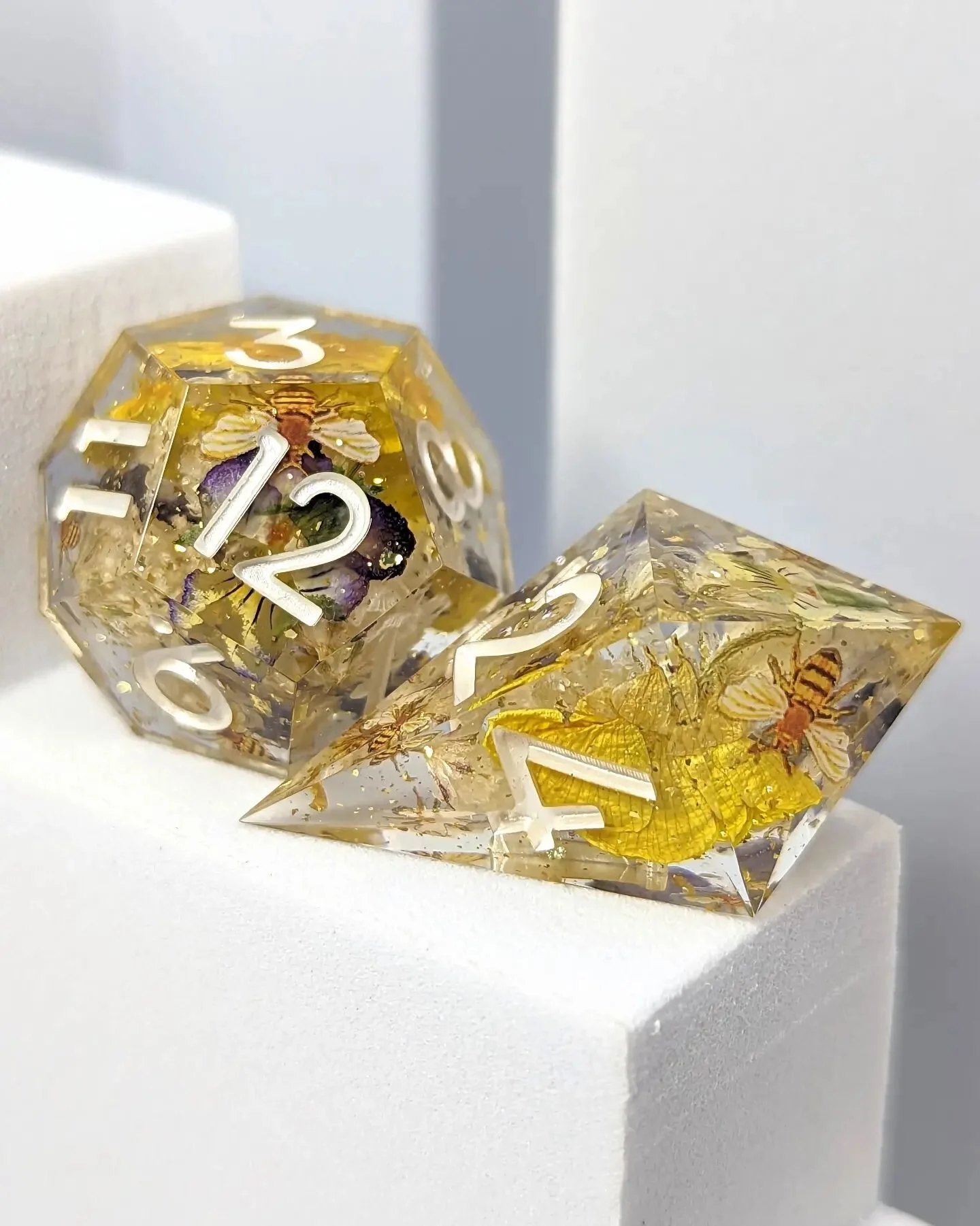 CW: real (deceased) insects
These glamour shots of this set really highlight the botanical inclusions&ndash; which flowers do you like best? 🌼

For anyone concerned about the ethical sourcing of the bee in one of the d20s for this set, never fear! N