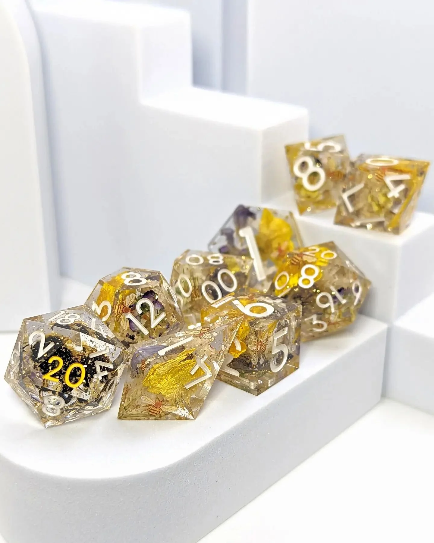 CW: real (but deceased) insect!
Hello bees! 🐝 This commission set is full of dried buttercups, baby's breath, tiny violets, and wisteria, along with gold flecks and plenty of adorable bee decals. And one of the d20s even includes a real bee!

(For t