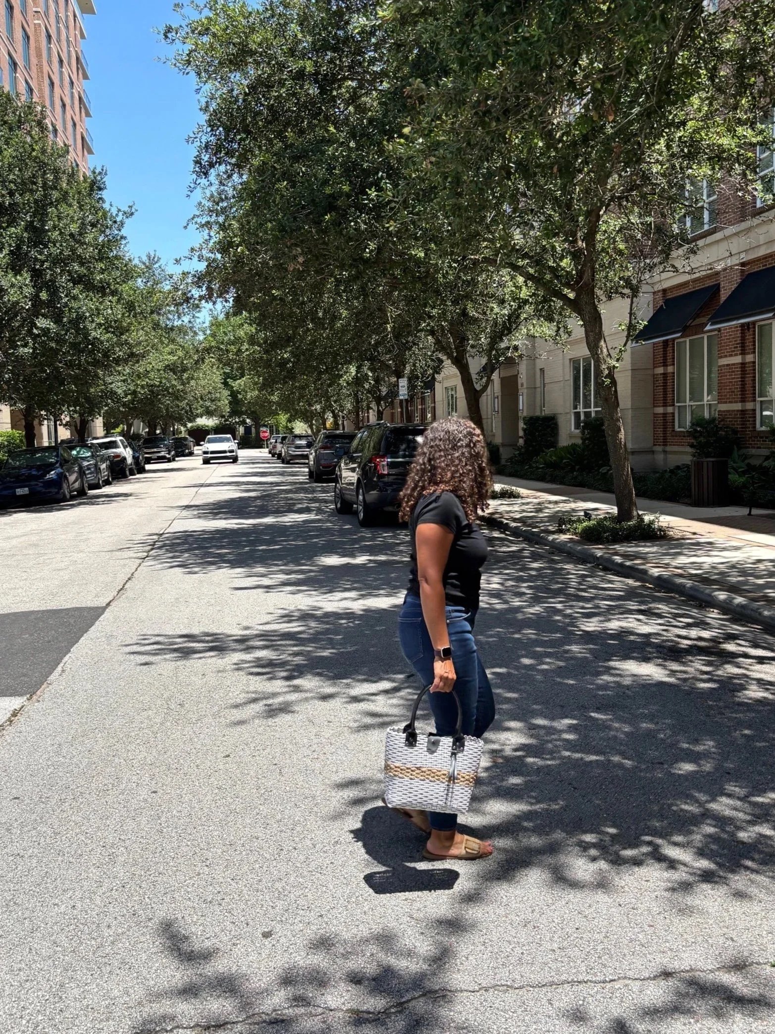 Lady walking with a handwoven black and white bag.
