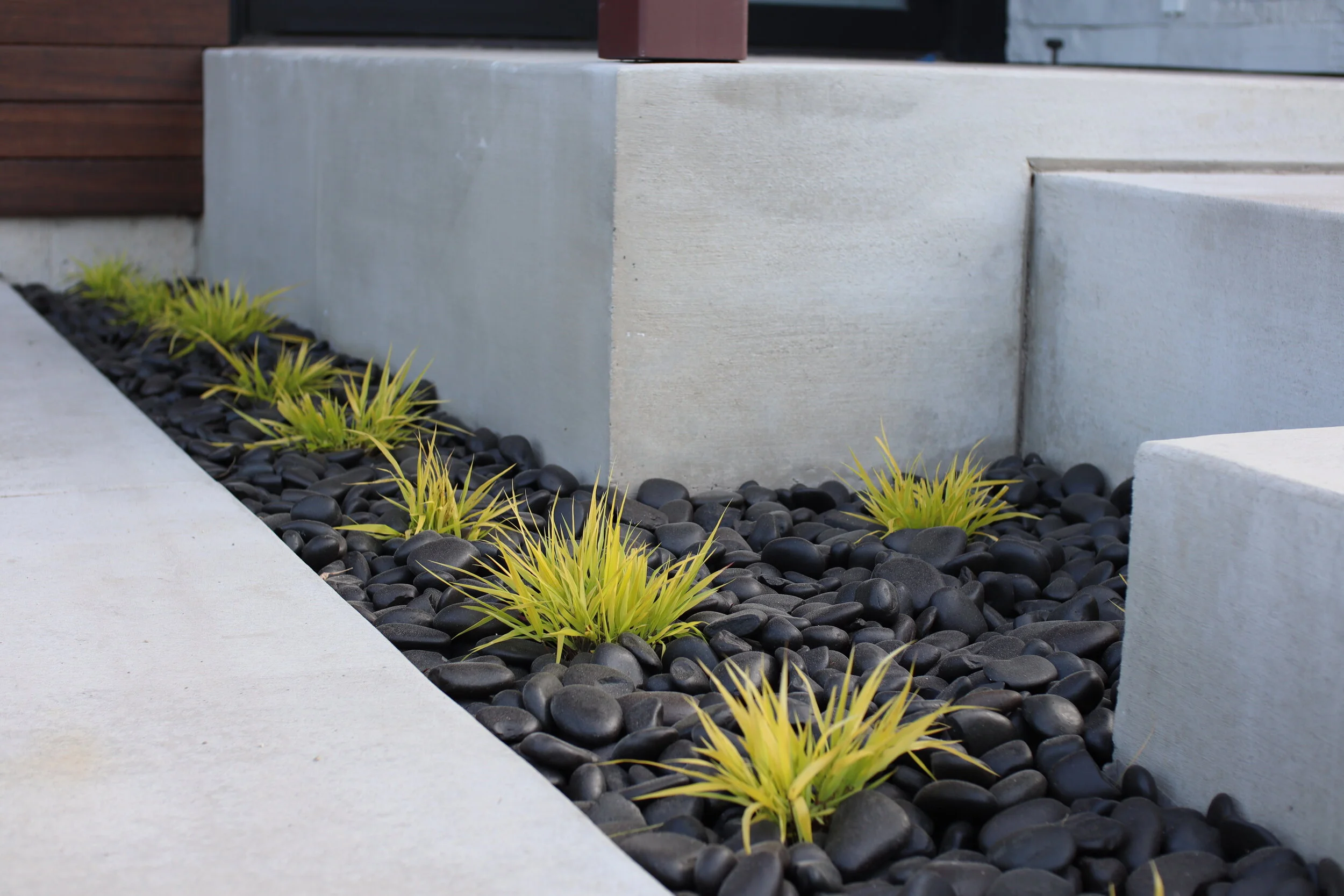 Japanese grass and black rock in a modern landscape bed in Missoula Montana