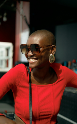 Woman smiling to side, wearing sunglasses and redshirt. Cancer depression therapist Pennsylvania Sarah Bryski-Hamrick
