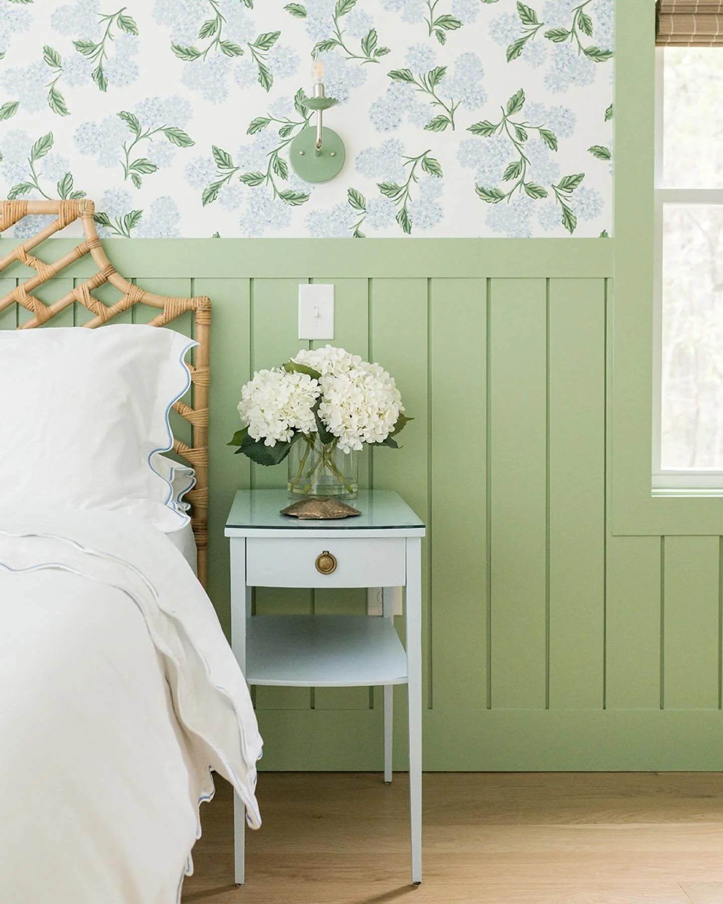 first up is the primary bedroom at the #preppyhollowhouse! we love this cheerful combination of hydrangea wallpaper from @riflepaperco paired with soft green paint for the trim and wall paneling&hellip;hydrangeas are a Cape Cod classic! a rattan head