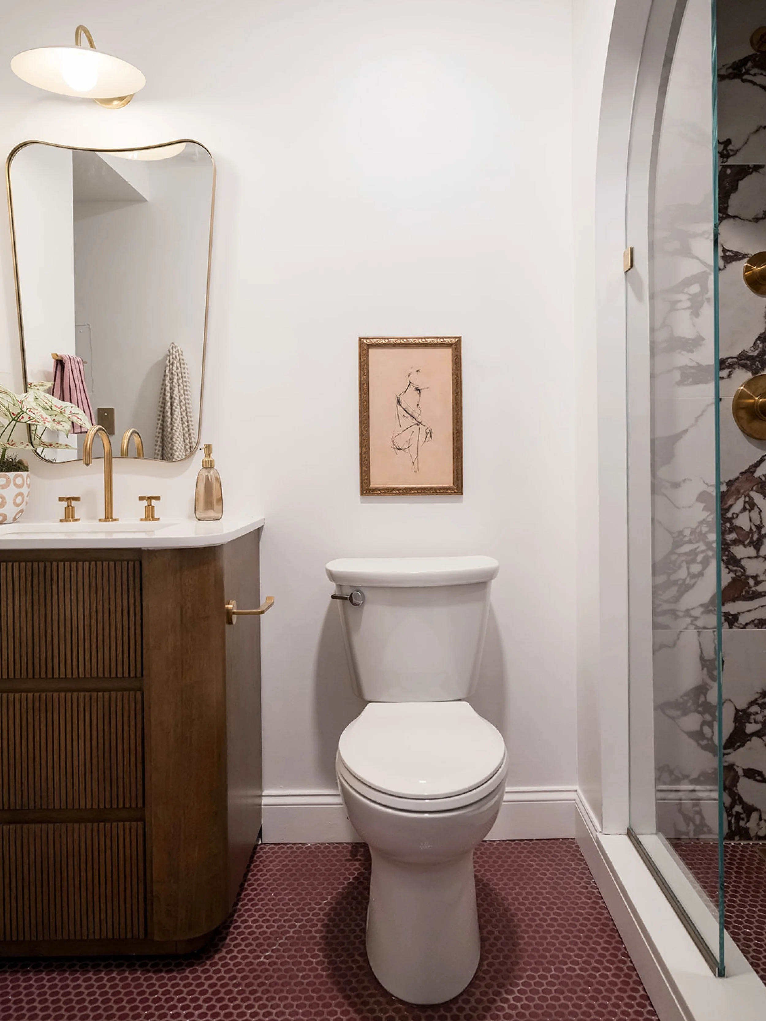 in contrast to the bright and airy bedroom space, #dwelloctoberstudio went with a moodier feel for the en suite bathroom, using deep plum penny tile for the floor, a Calacatta Viola-inspired tile for the shower walls, and a rich wood vanity. brushed 