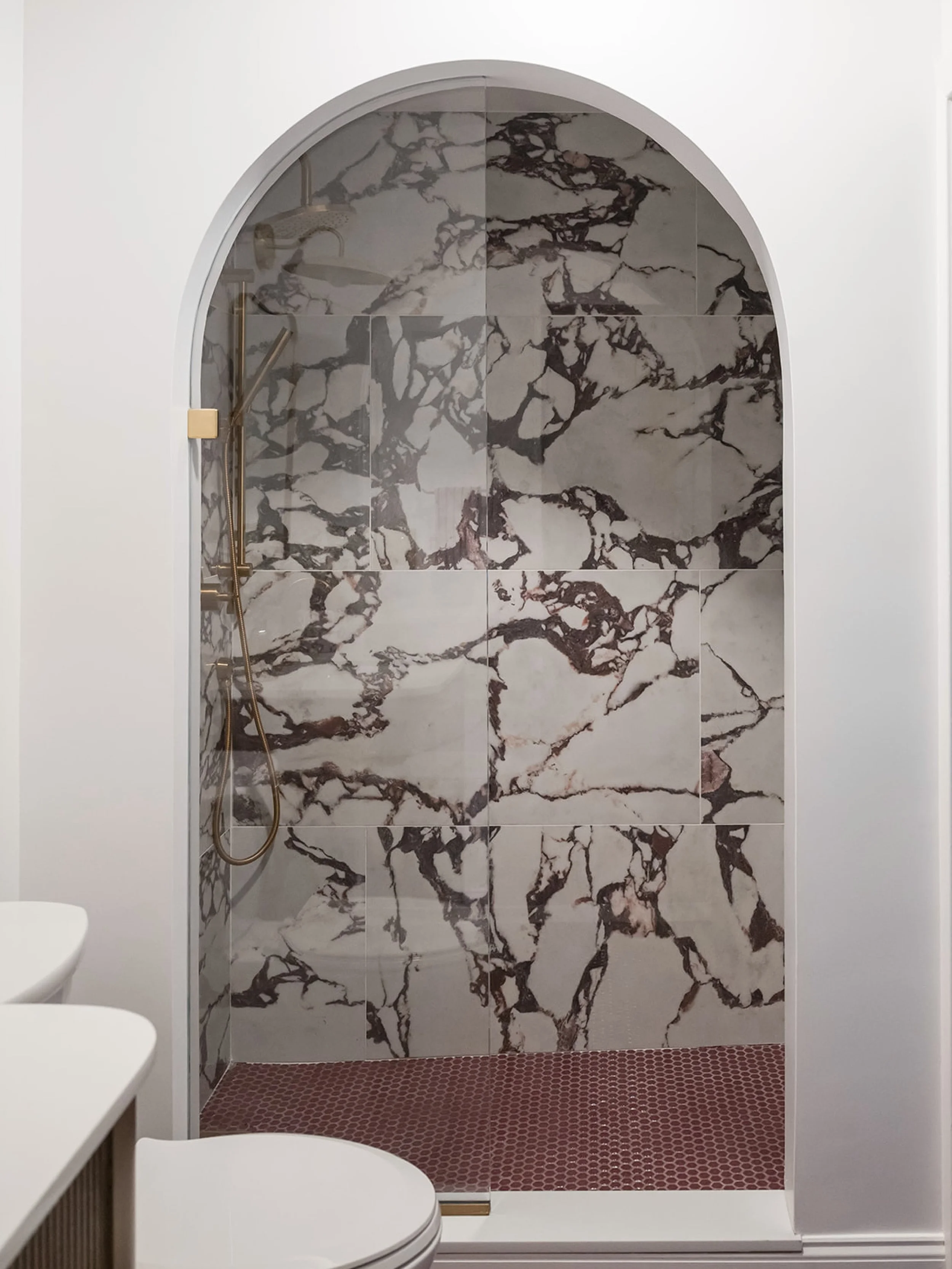 when updating the bathroom at this #dwelloctoberstudio project, we were inspired to convert the tub/shower unit into a walk-in shower with a dramatic arched entry. we selected a bold Calacatta Viola-inspired large format porcelain tile for the shower