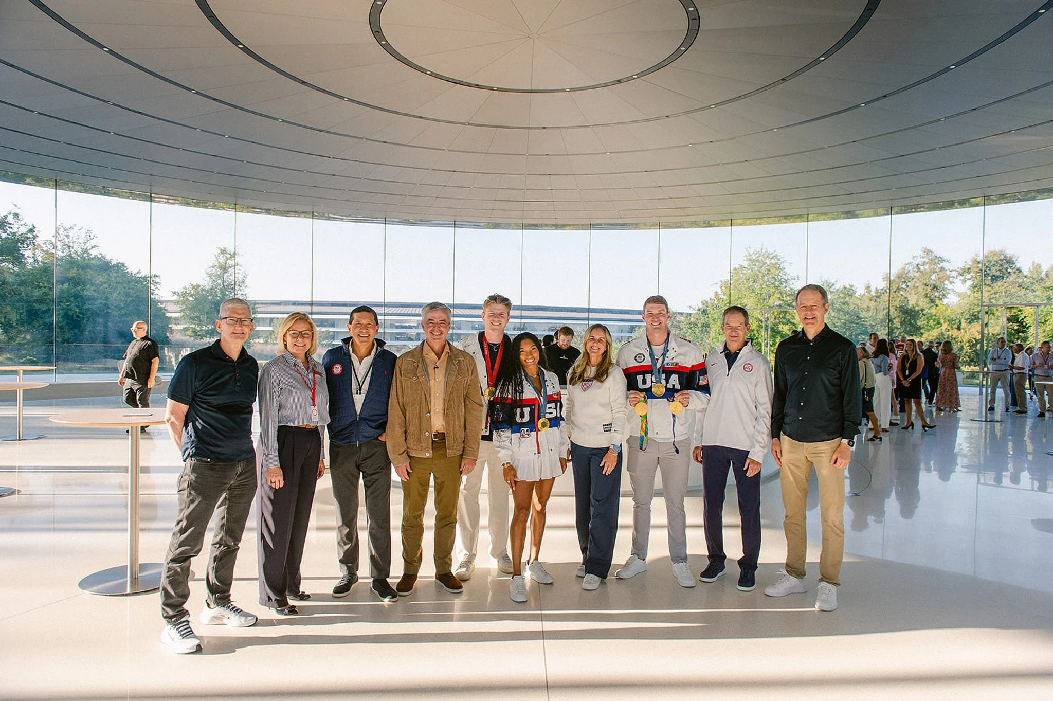 Group portrait of executives and Team USA Olympians in front of the infinite loop glass wall at Apple HQ in Cupertino. Silicon Valley executive event photography by Michaela Joy Photography.