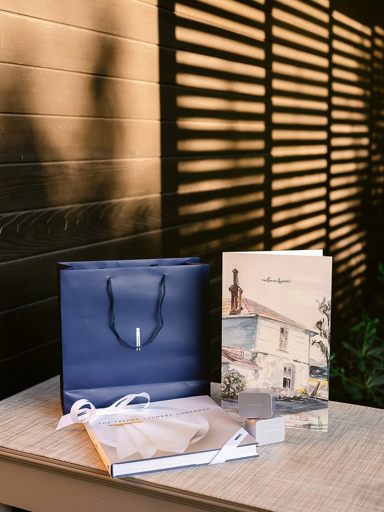 Sophisticated detail of corporate gifting, including The French Laundry branded tote bags, set at an exclusive Napa Valley dinner event. Luxury retreat branding details by Michaela Joy Photography.