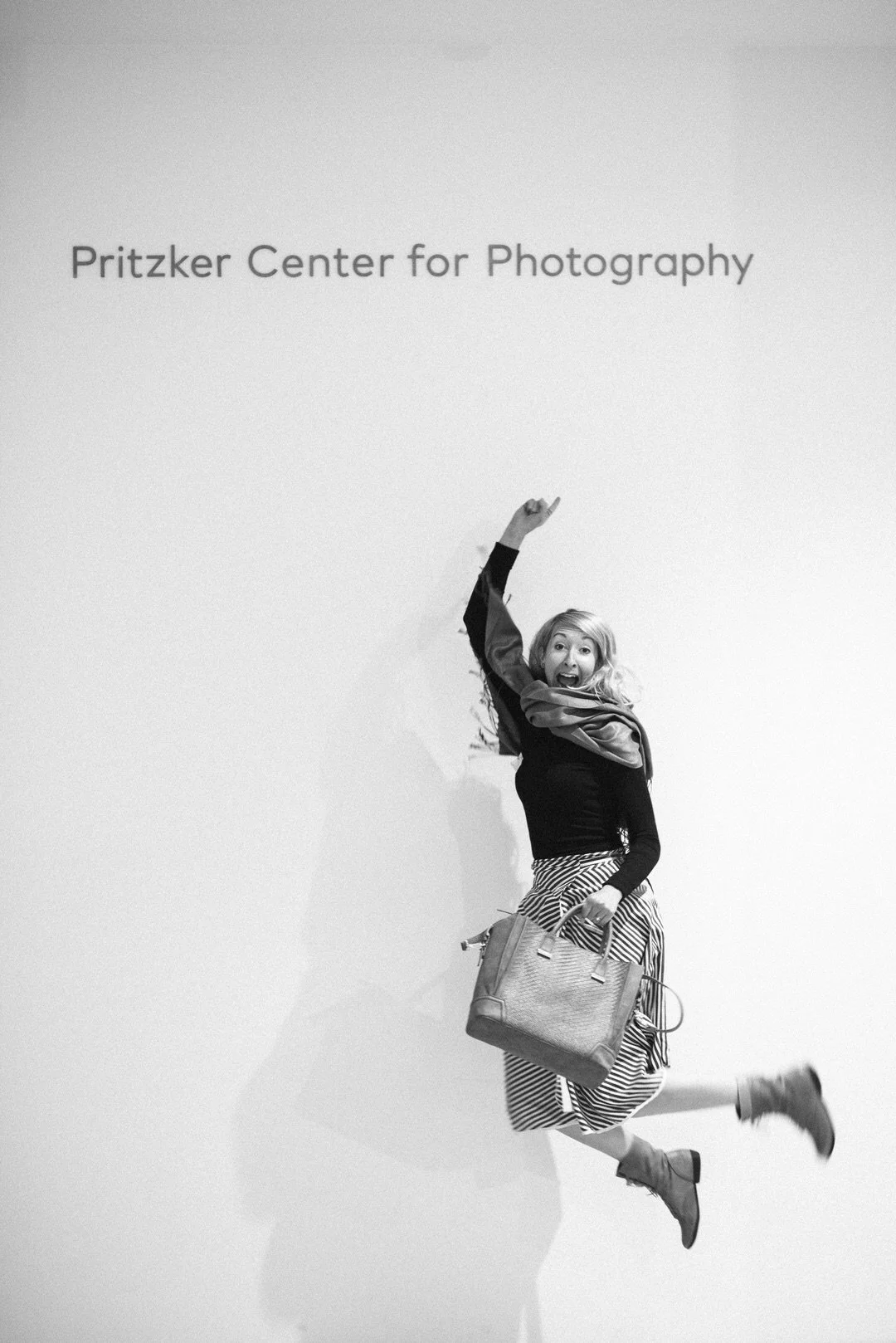 Michaela Joy jumping cheerfully near the Pritzker Center for Photography, representing creative growth and business mentorship.