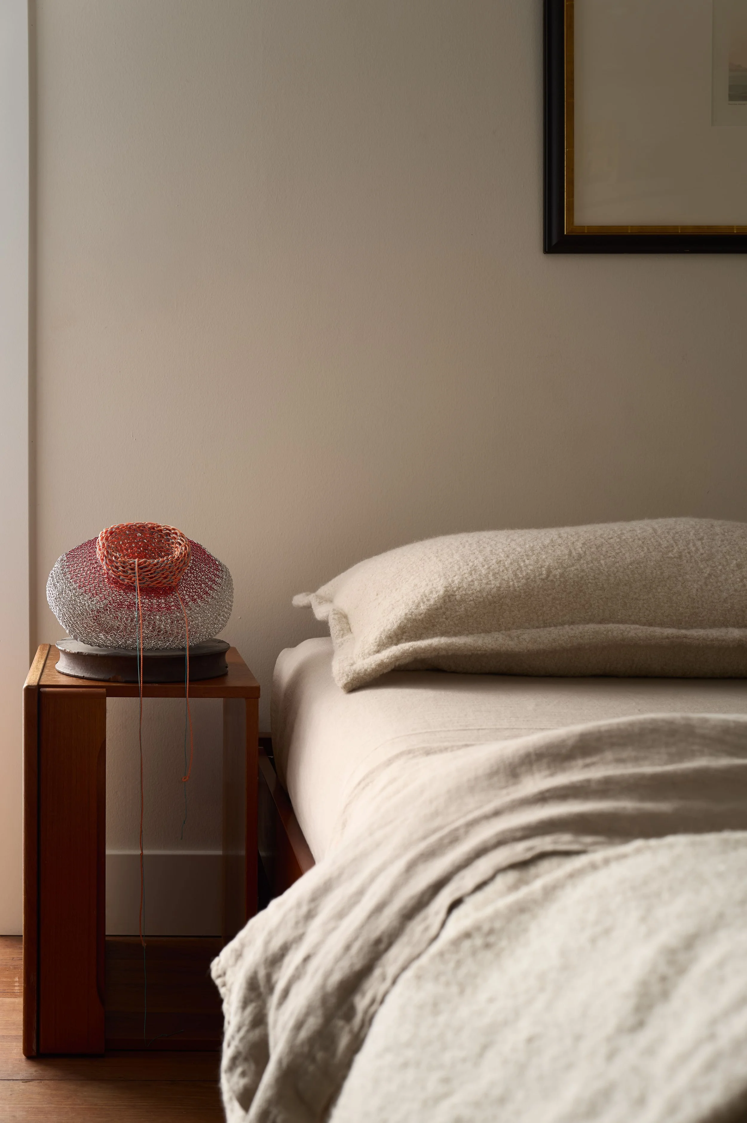 Bedroom pillow detail with a woven red and white ceramic lamp on a wood nightstand, Alamo Farmhouse (Jackson Way) complete furnishing and interior architecture remodel by Spearman Spaces