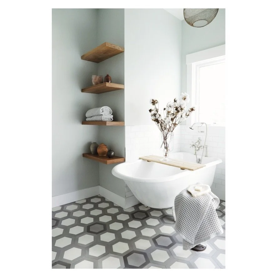 Freestanding clawfoot tub with black and white hexagonal floor tile and floating wood shelves, Oakland Bungalow (61st Street) full-service remodel by Spearman Spaces
