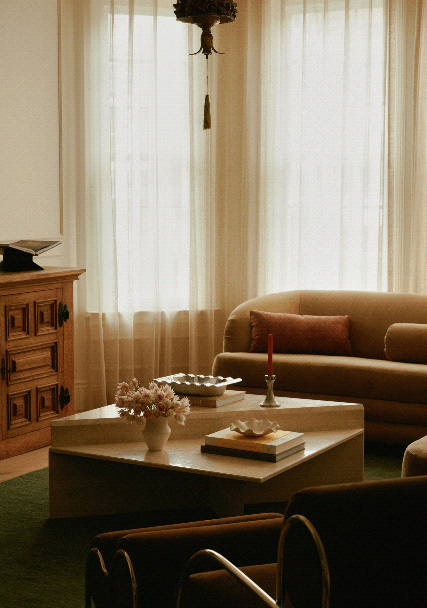 Modernized historic living room with camel curved sofa, rust throw pillow, and travertine coffee table, San Francisco Modern Victorian (11th Avenue, Inner Sunset) remodel by Spearman Spaces