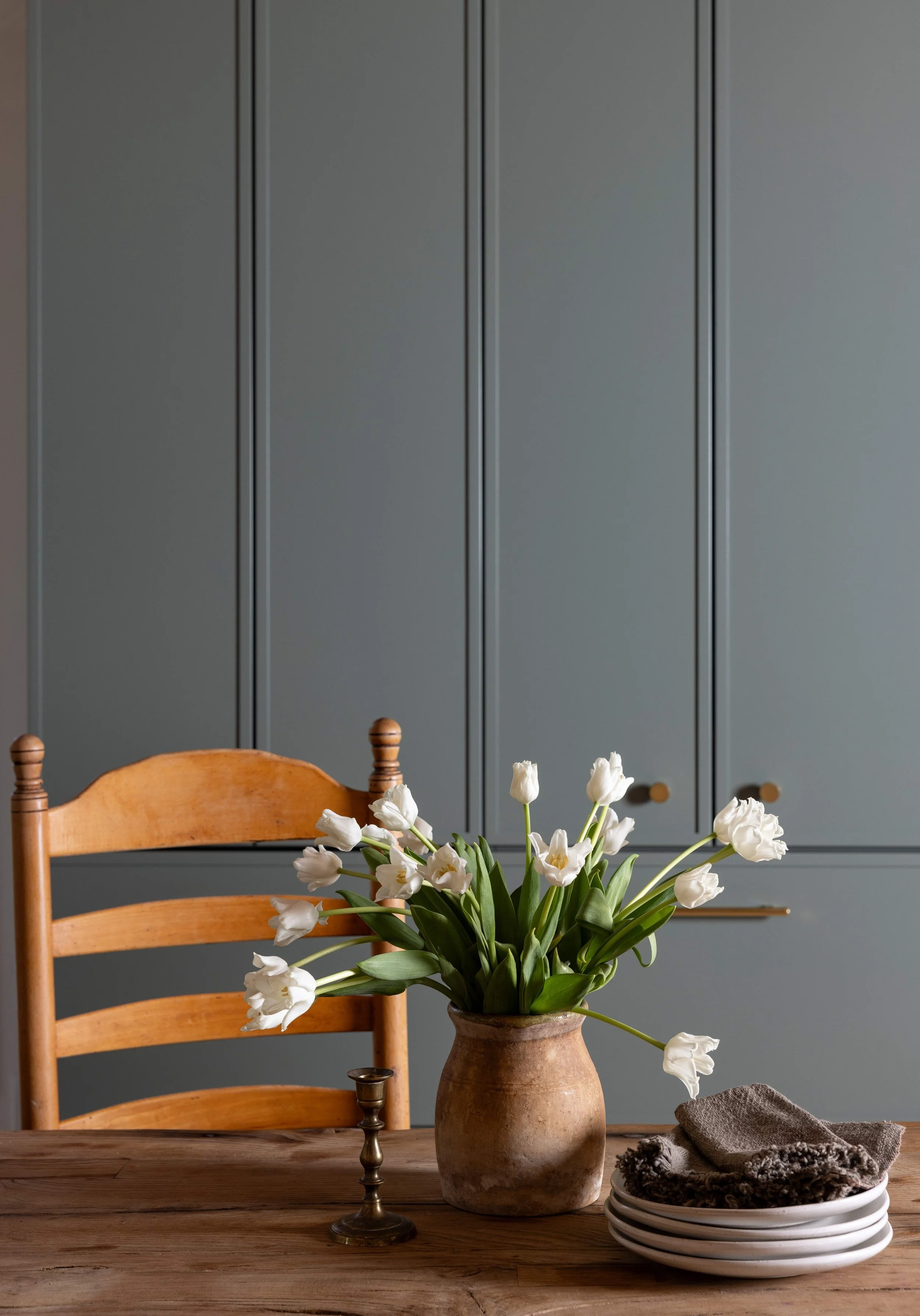 Antique pine farm table styled with white tulips and stacked plates against blue-grey shaker cabinetry, Marin County Craftsman whole-home remodel by Spearman Spaces