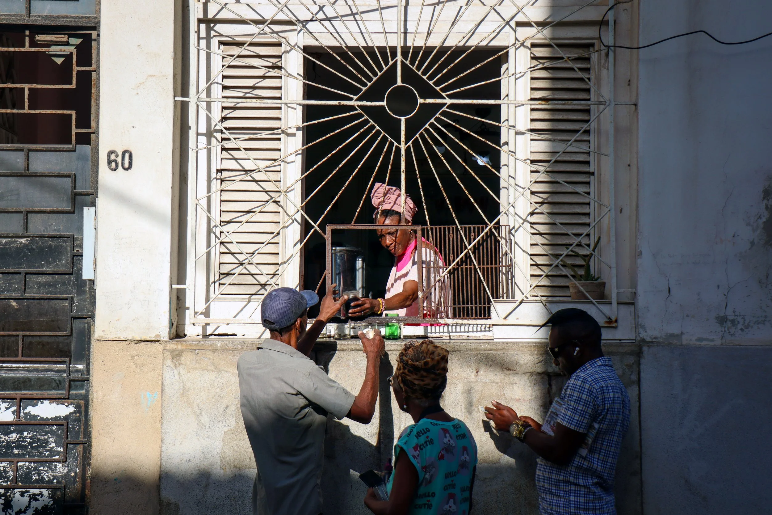 HAVANA, CUBA — March 7, 2026: A woman serves coffee from her window in Old Havana (Habana Vieja), one of many small, informal pop-up setups Cubans have turned to in order to earn extra income