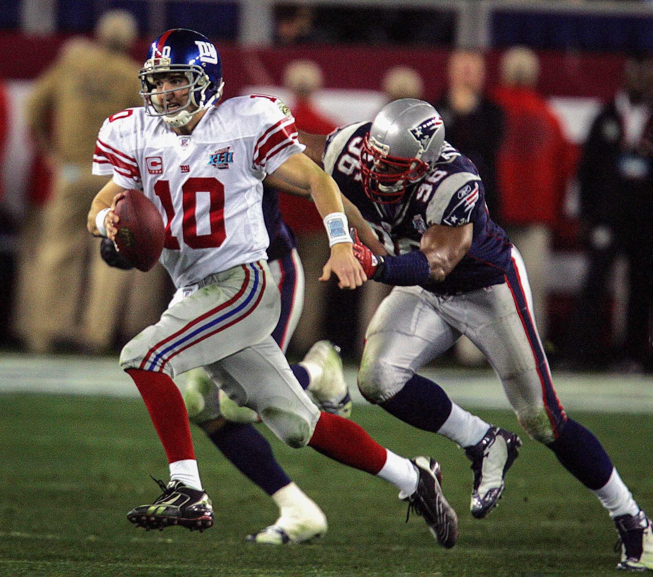 With his team trailing 14-10 with 2:42 remaining QB Eli Manning escapes Patriot defenders to complete an improbable past to wide receiver, David Tyree.