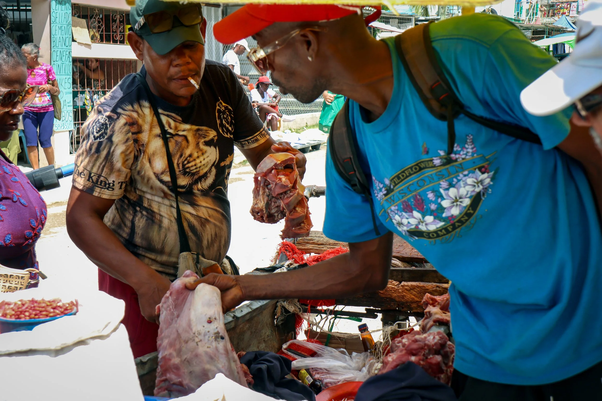 HAVANA, CUBA — March 8, 2026: Two men complete a transaction for raw meat from a pushcart in a crowded market in La Güinera, where limited sanitation creates challenging and potentially unsafe conditions for handling food.