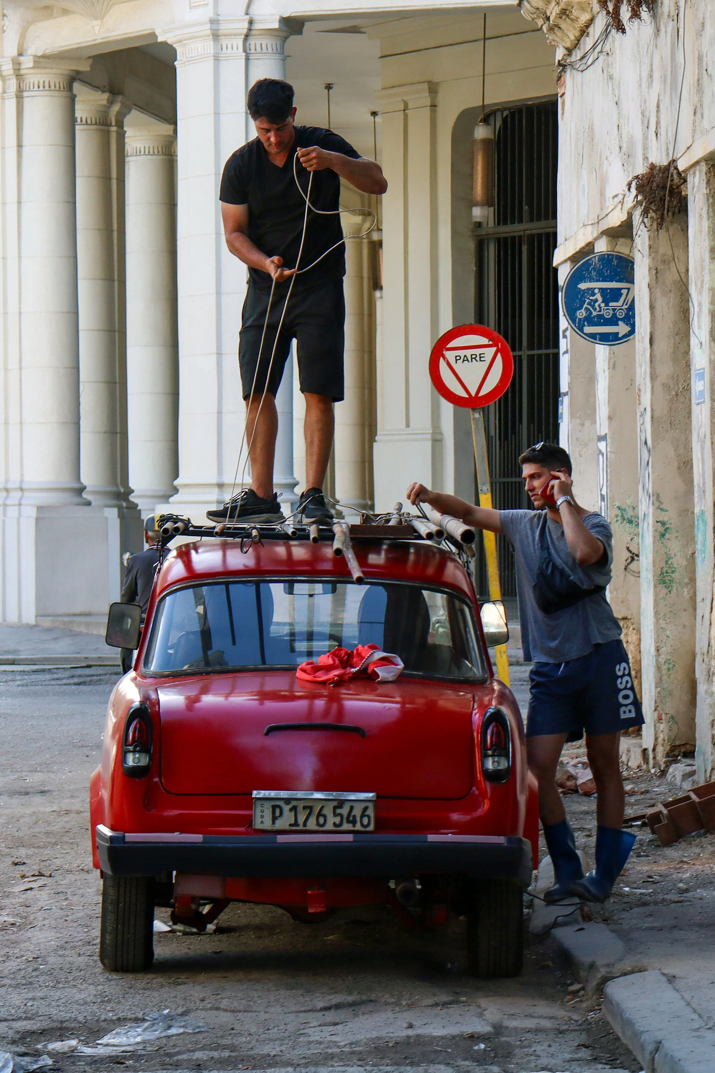 HAVANA, CUBA — March 8, 2026: A man stands on the roof of a car securing items for transport, as fuel shortages have limited the use of automobiles and forced residents to make the most of available trips.