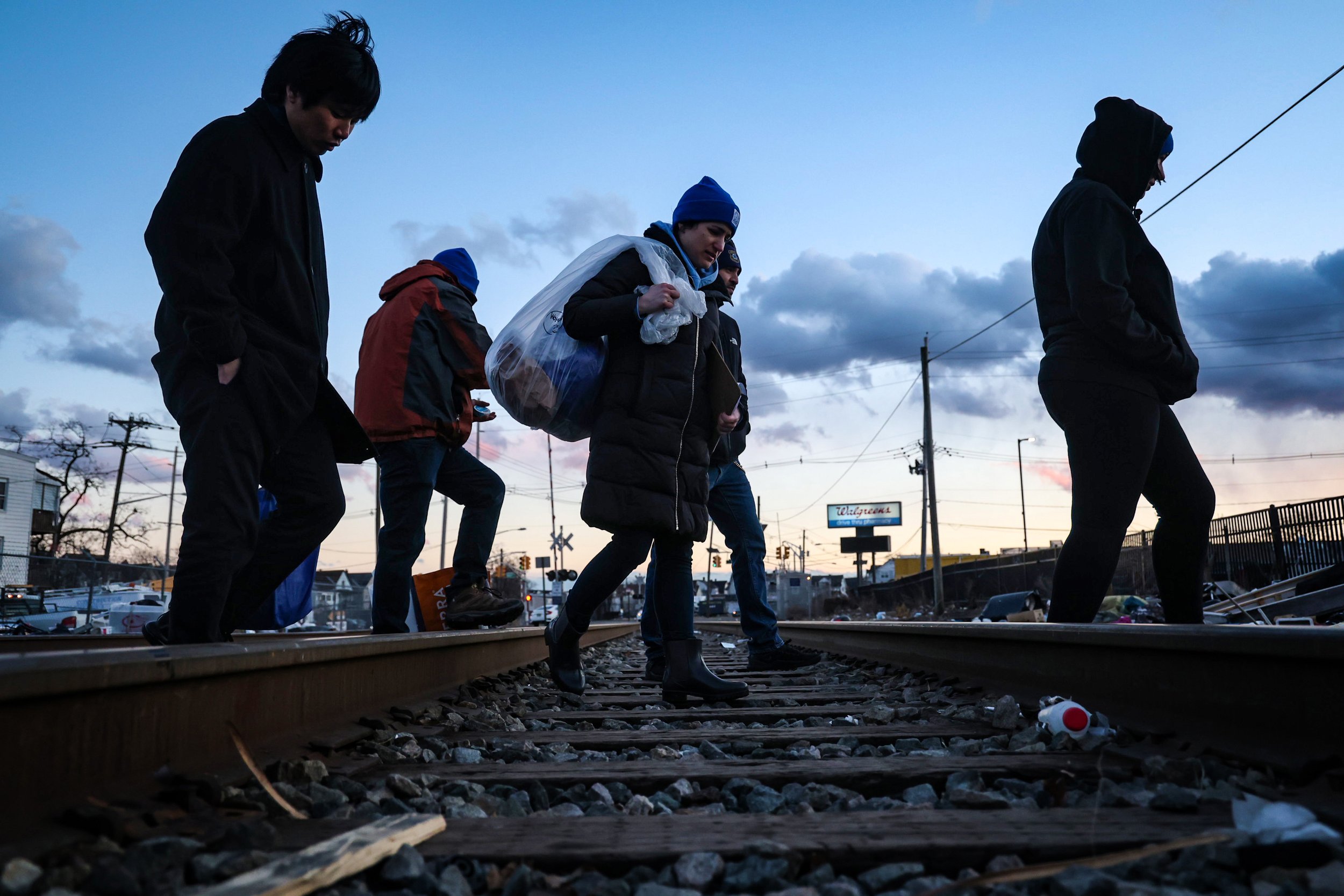 PATERSON, N.J. | 01-29-2025: AmeriCorps members and volunteers canvas the area along the train tracks near a homeless encampment at dusk while conducting the annual Point-in-Time (PIT) Count, a nationwide effort to document homelessness on a single n