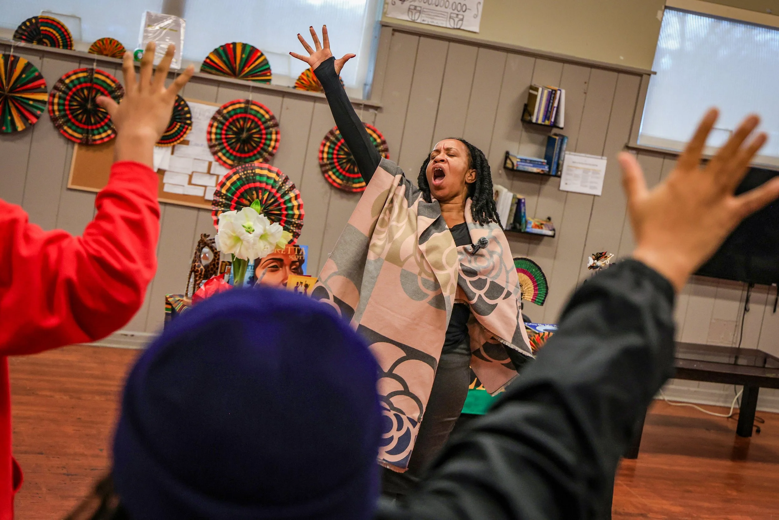 PATERSON, N.J. | December 30, 2025: Talina Queen raises her hand while leading a libation—a call-and-response ritual honoring ancestors and community members who have passed—during a Kwanzaa observance at the Great Falls Youth Center. Queen led a wee