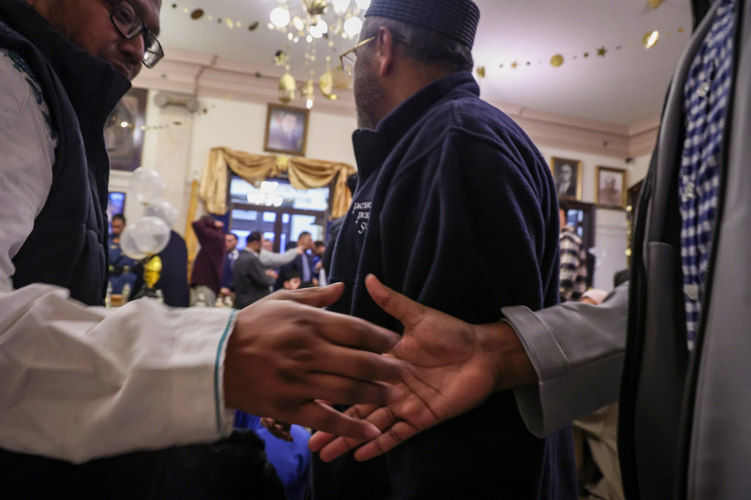 PATERSON, N.J. | 03-13-25 — COMMUNITY IFTAR: Two men shake hands upon arriving at the annual Ramadan Iftar at City Hall, where approximately 300 interfaith community members gathered to break the fast at sunset. Home to New Jersey’s largest Muslim po