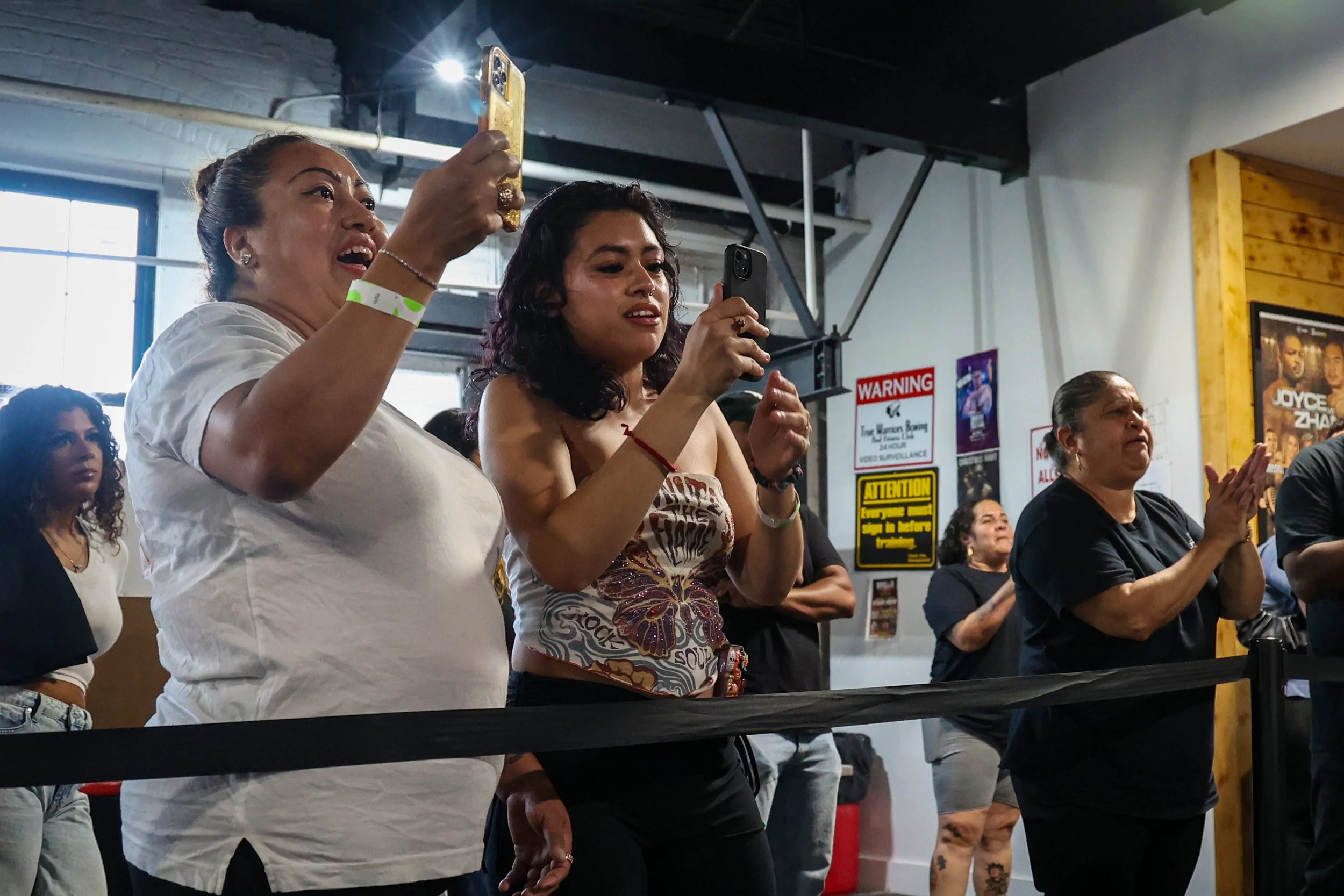 Erik Mendez’s mother Ana Mendez and his  fiancé Joselyn Cano record his fight at the True Warrior gym. 
