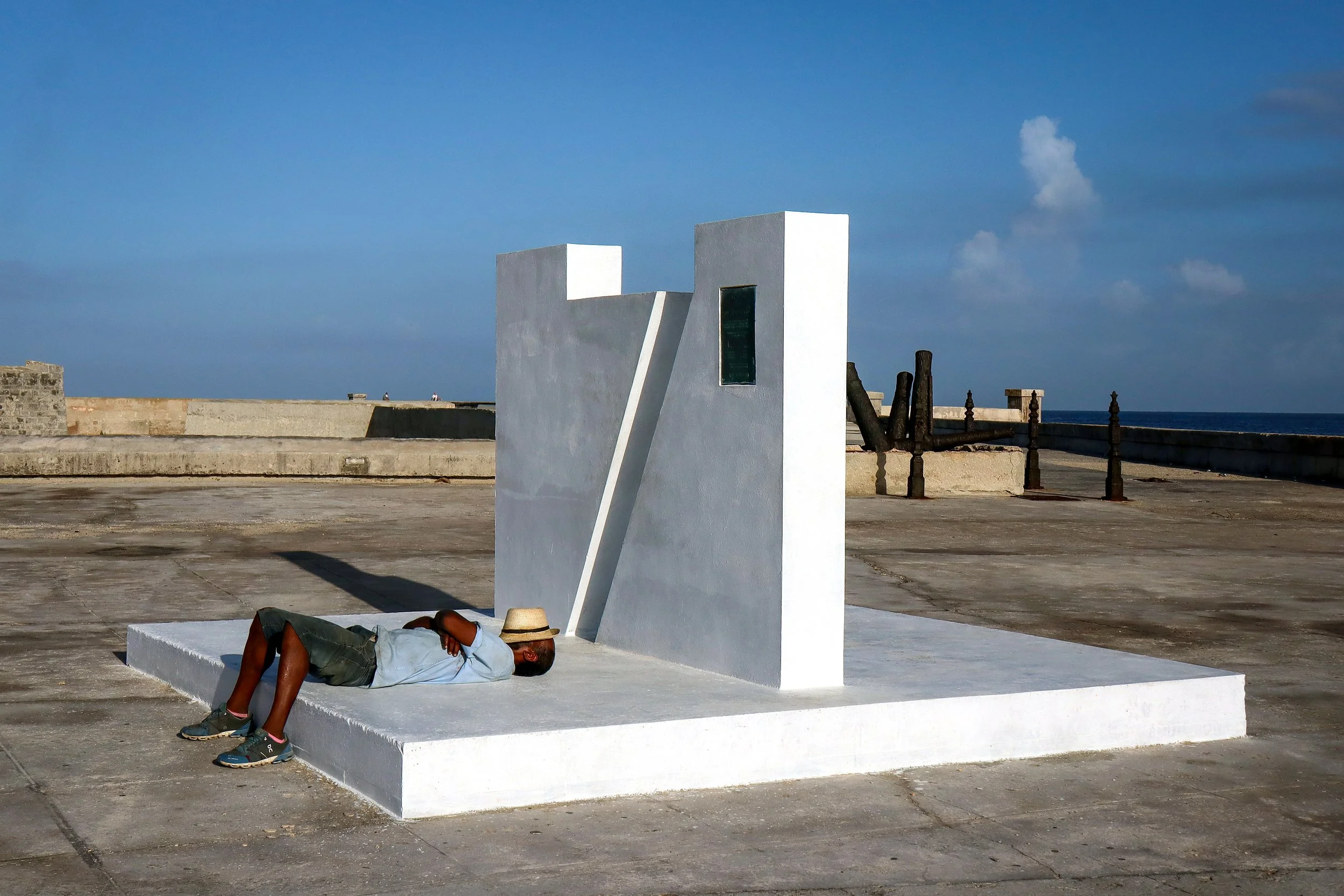 HAVANA, CUBA — March 8, 2026: A man sleeps in the early morning light, lying on a monument near Havana Harbor (Puerto de La Habana).