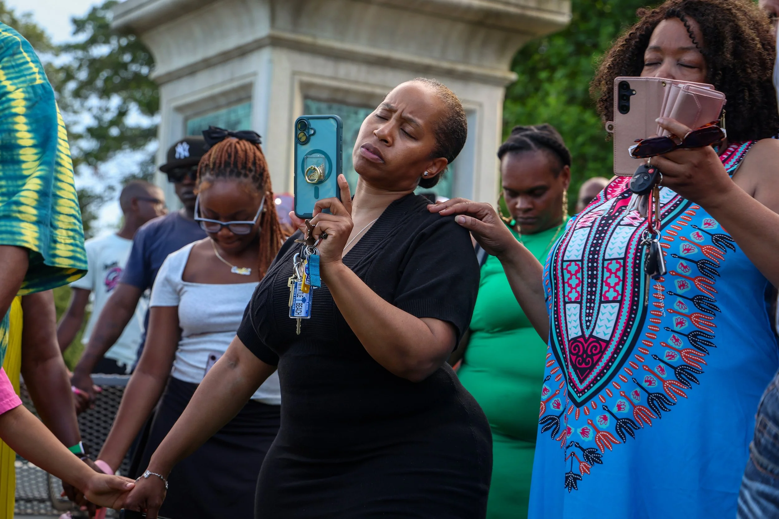 PATERSON, N.J. | June 18, 2025: Members of Paterson’s African American community hold hands and record with their phones during a moment of prayer at the annual Juneteenth Community Flag Raising and Prayer Gathering at Eastside Park. Juneteenth—Emanc