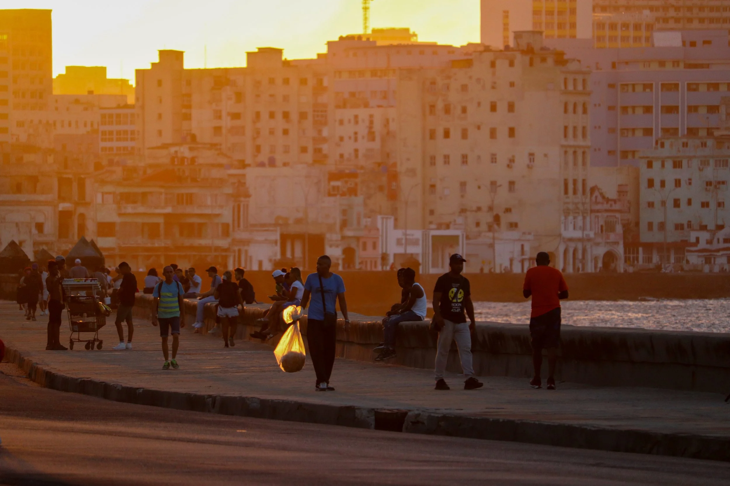 HAVANA, CUBA — March 9, 2026: A man carries a bag along the Malecón at sunset, briefly illuminated by the fading light as he walks along the seawall.