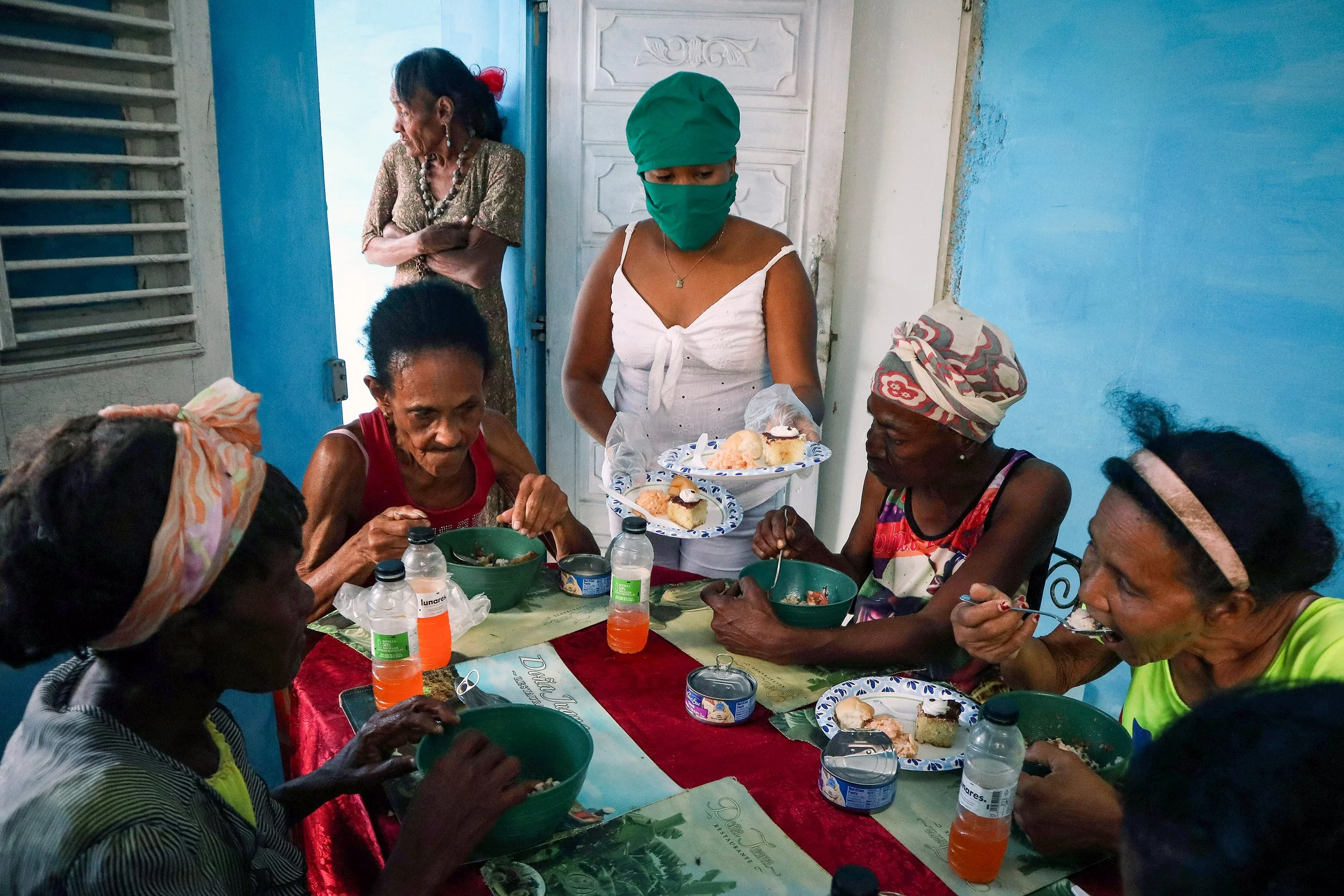 HAVANA, CUBA — March 8, 2026: Elderly residents in La Güinera  eat a meal prepared by Iliana Macias Pulido, known as “Mama,” and her team. Many show visible signs of hardship as they gather at the community kitchen. The food was supplied by Chuck Faz