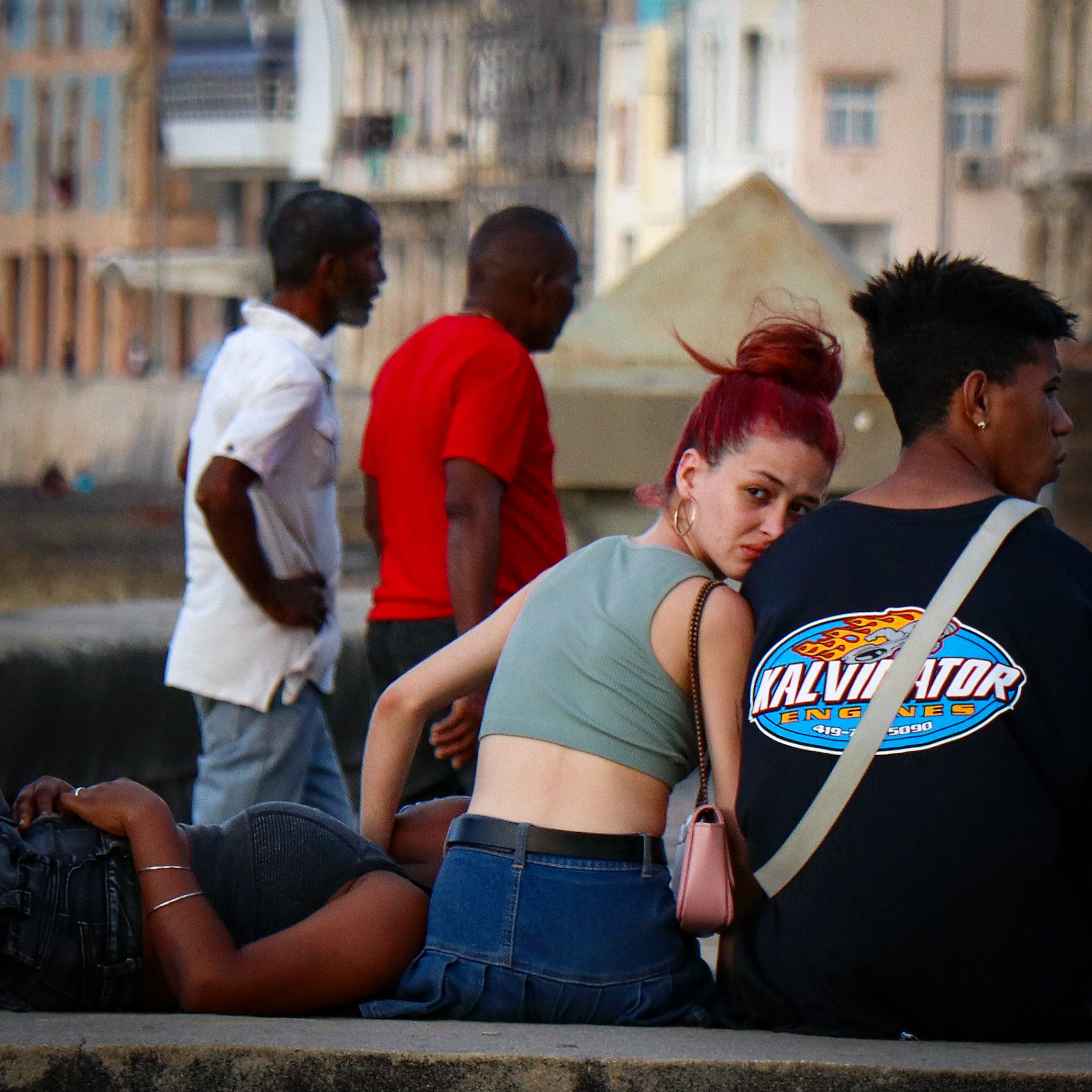 HAVANA, CUBA — March 8, 2026: A teenage girl looks back while sitting with friends on the seawall along the Malecón (Malecón de La Habana) in Havana.