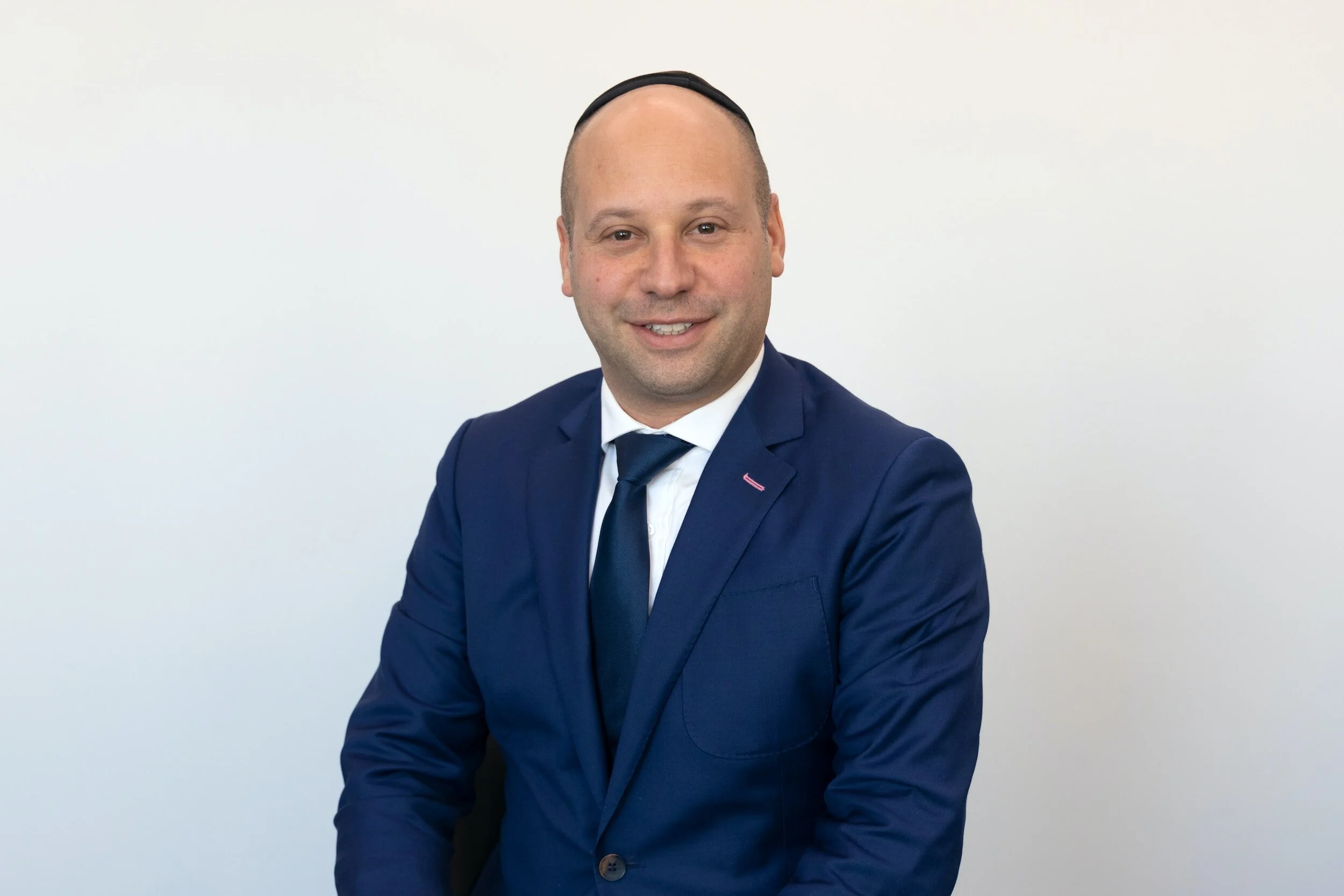 Headshot of businessman in suit and tie with receding hairline and a friendly smile