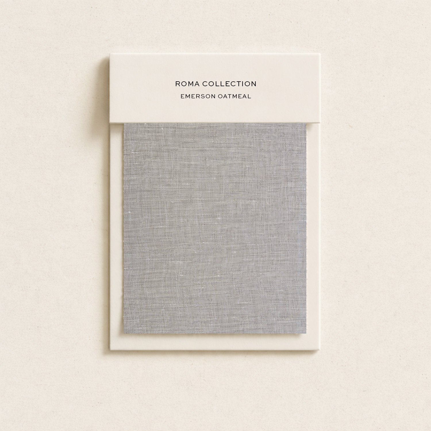 A fabric sample display board showing a grey linen-textured swatch with a white label reading 'ROMA COLLECTION EMERSON OATMEAL' at the top.