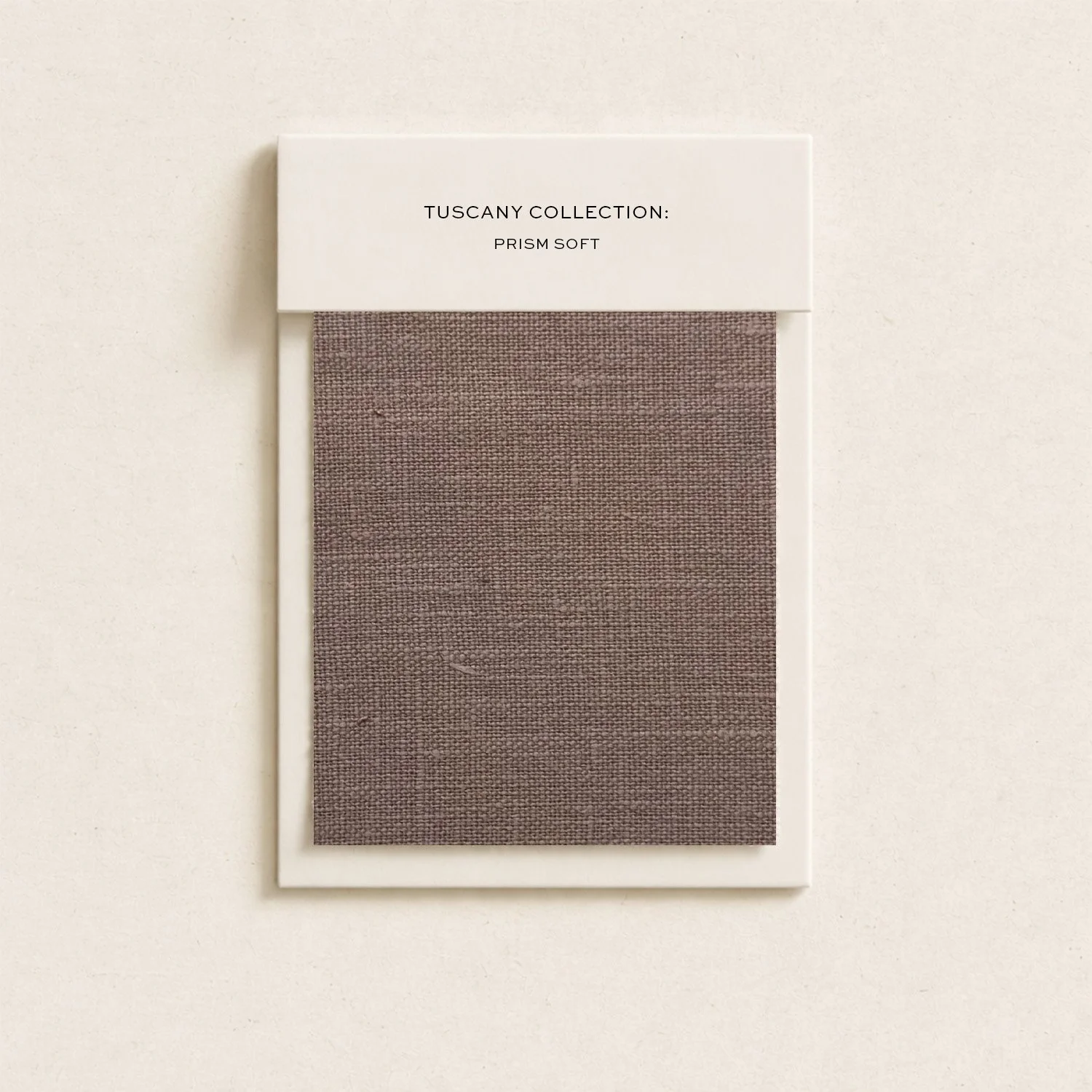 Sample fabric swatch showing a brownish, textured textile. The swatch is mounted on a white card labeled 'Tuscany Collection: Prism Soft' and is positioned against a light-colored background.