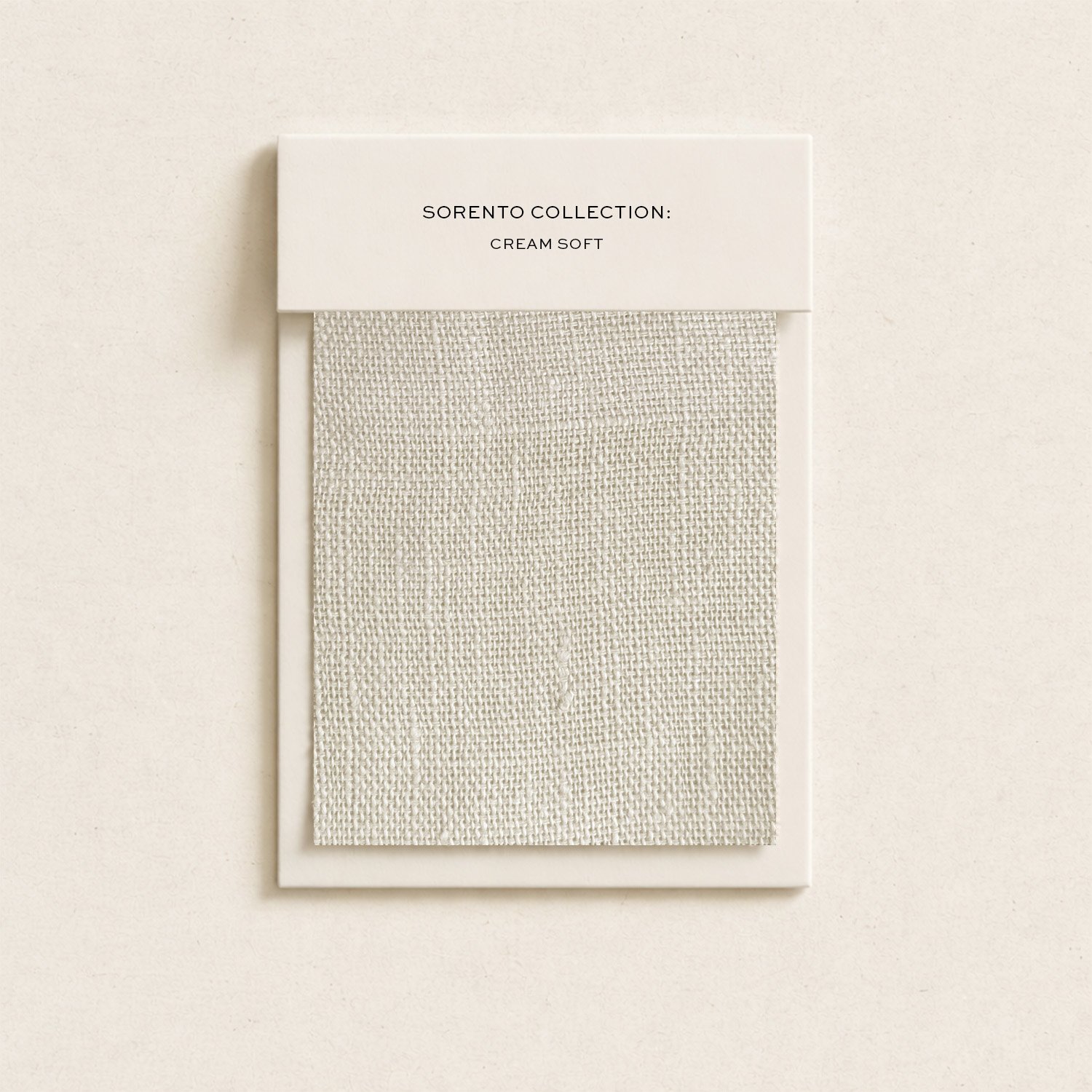 Cream-colored fabric swatch sample attached to a cardboard backing, labeled 'Sorento Collection: Cream Soft' on a white card. The fabric has a textured, woven appearance.