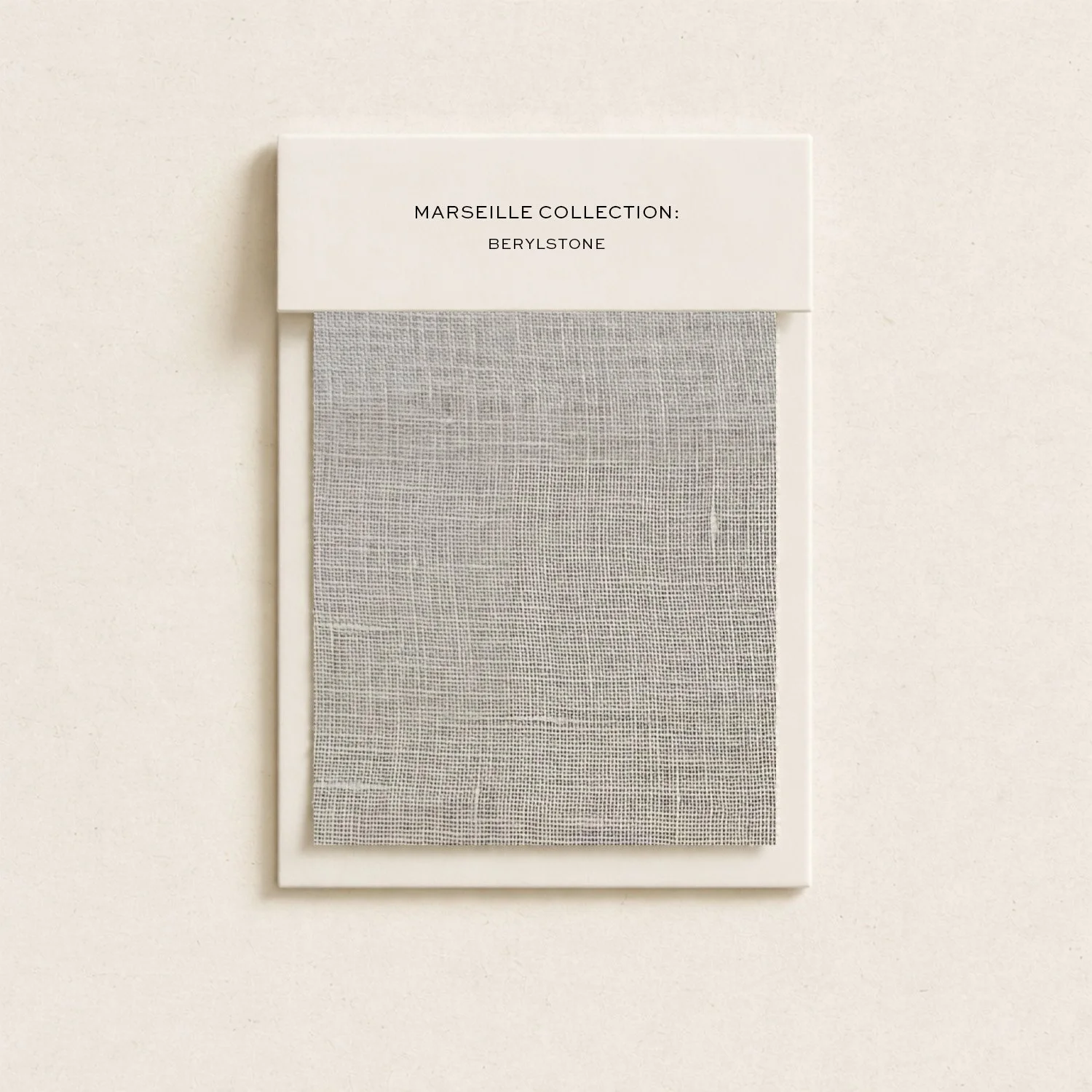 Sample swatch of a light gray fabric from the Marseille Collection: Beryllstone, attached to a white display card with black text.