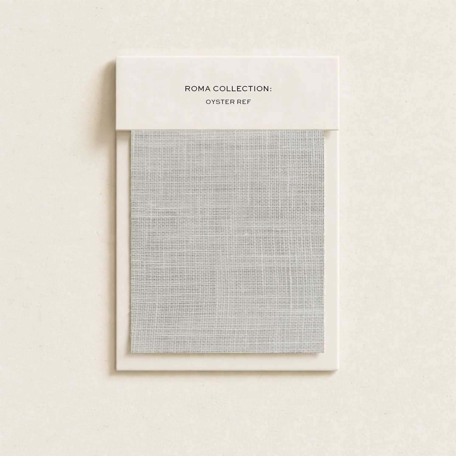 Sample of a fabric swatch from Rome Collection: Oyster Ref, displayed in a white frame against a light-colored wall.