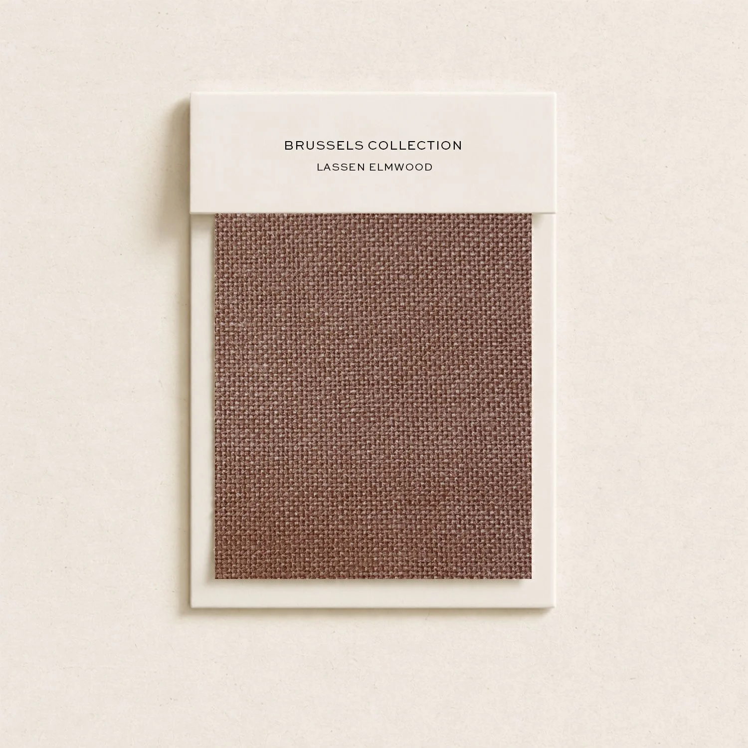 A fabric swatch card from the Brussels Collection by Lassen Elmwood, featuring a textured, reddish-brown woven fabric.
