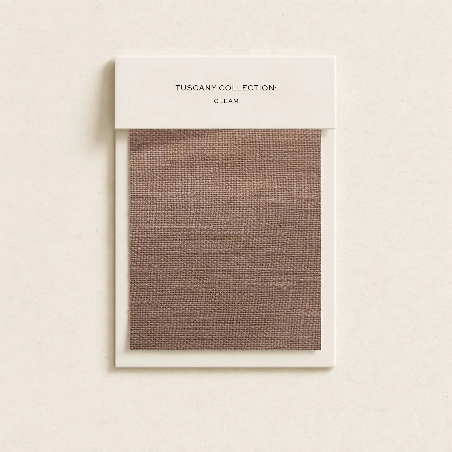 Swatch of brown fabric sample on a white card labeled 'Tuscany Collection: Gleam' mounted on a white background.