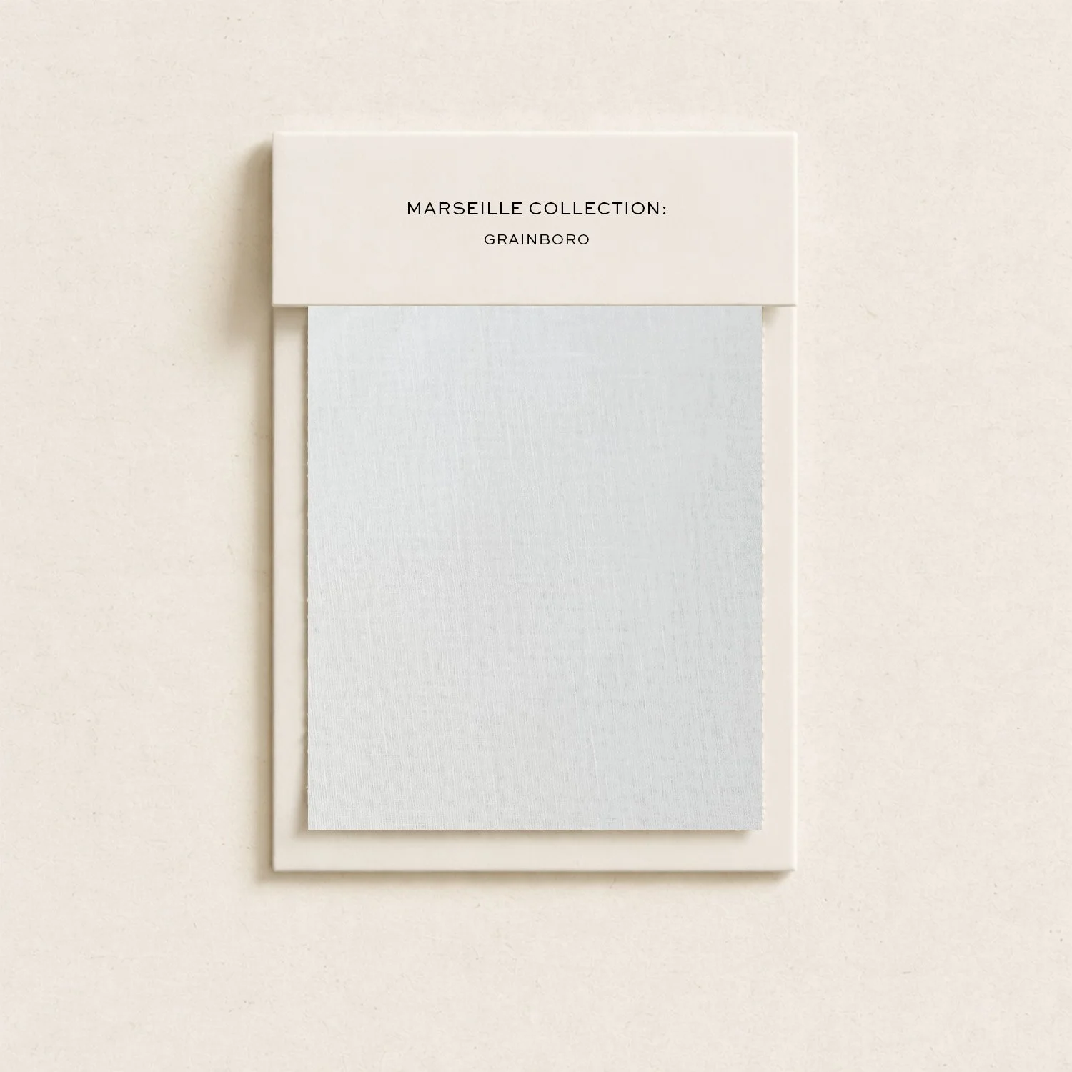 A display with a white box on a light-colored wall. The box reads, 'Marseille Collection: Grainboro,' with a piece of textured paper hanging below.