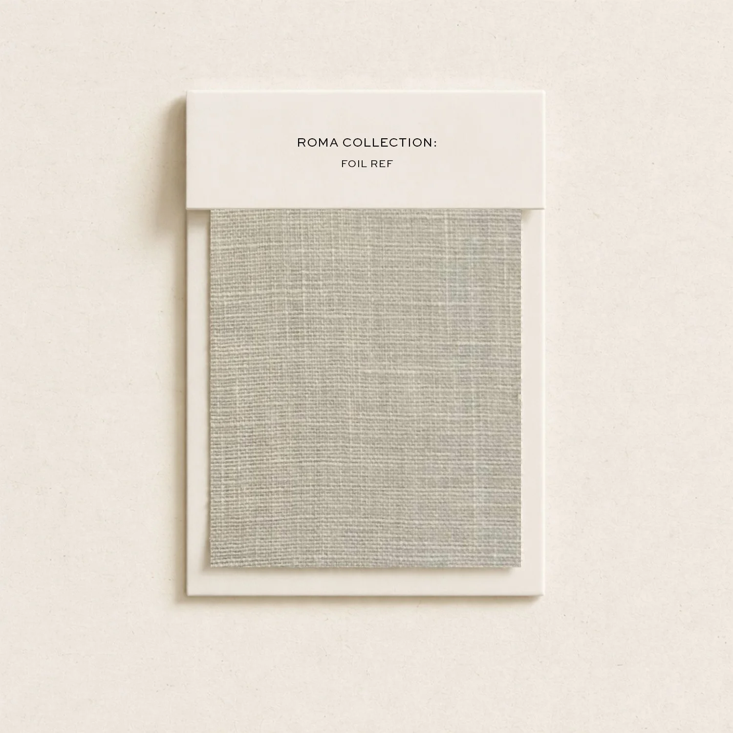 A fabric sample card from the Roma Collection displaying a neutral-colored fabric with a linen-like texture, mounted on a white background with a white label at the top reading 'ROMA COLLECTION: FOIL REF'.